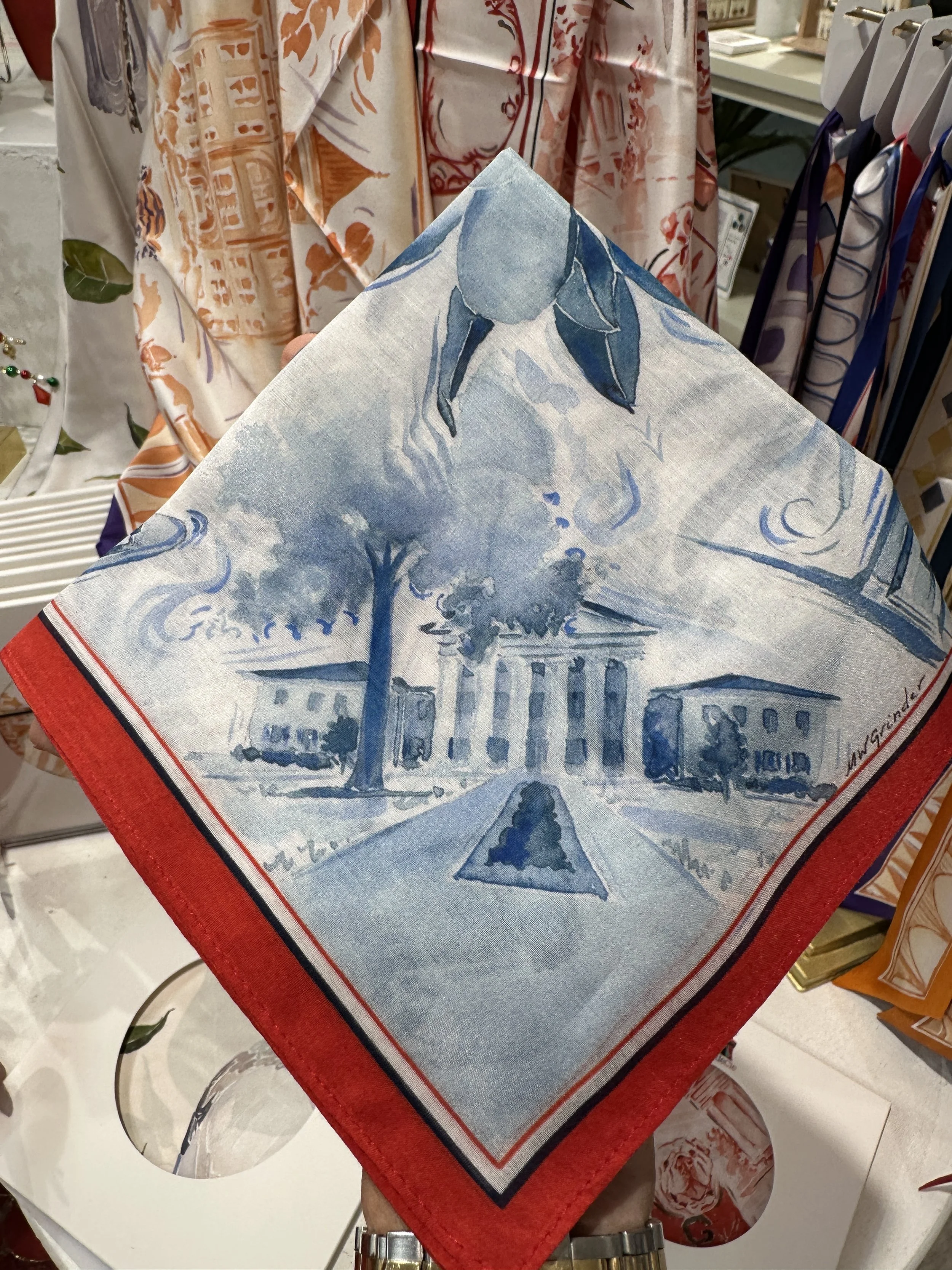 Ole Miss watercolor silk cotton pocket square by Megan Grinder, with magnolias and campus landmarks in blue inside a red border