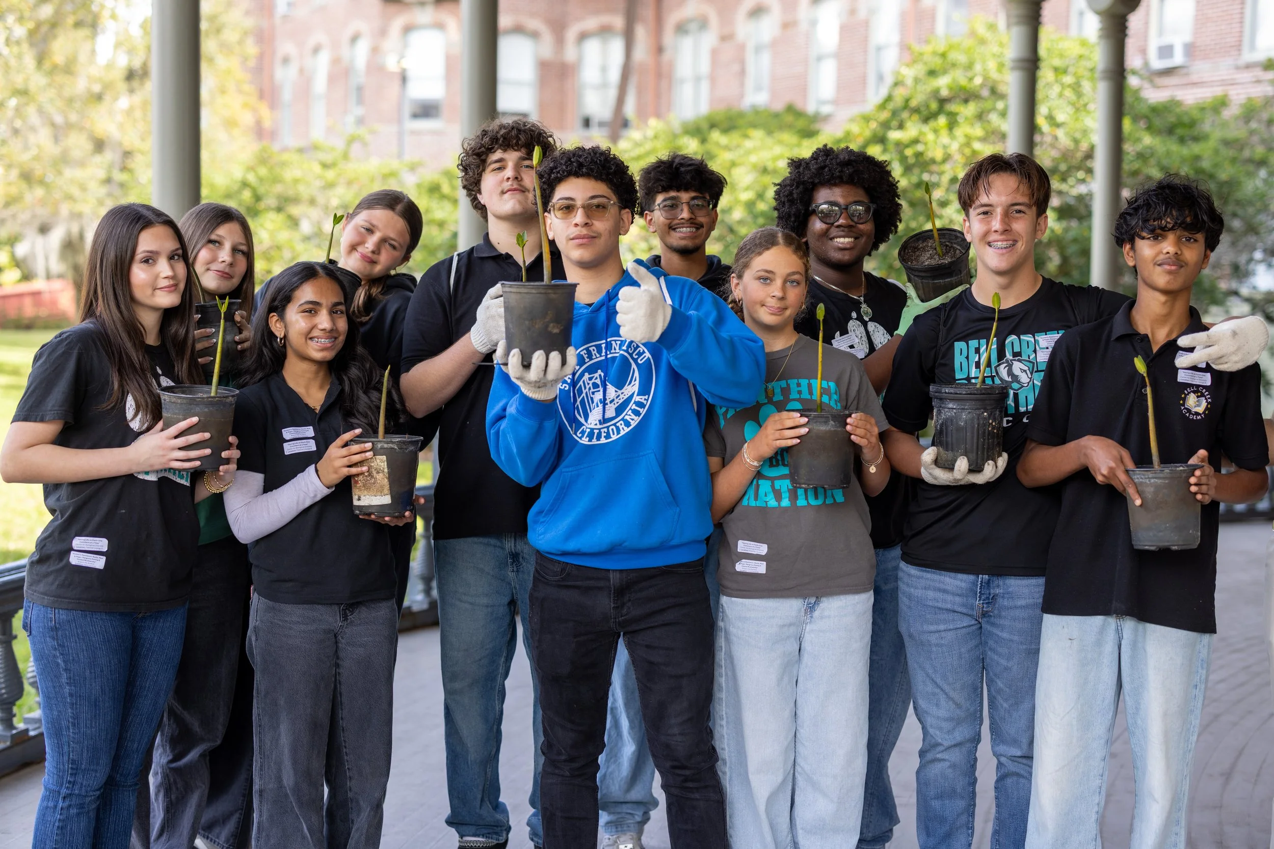 group photo of students holding potted mangrove plants