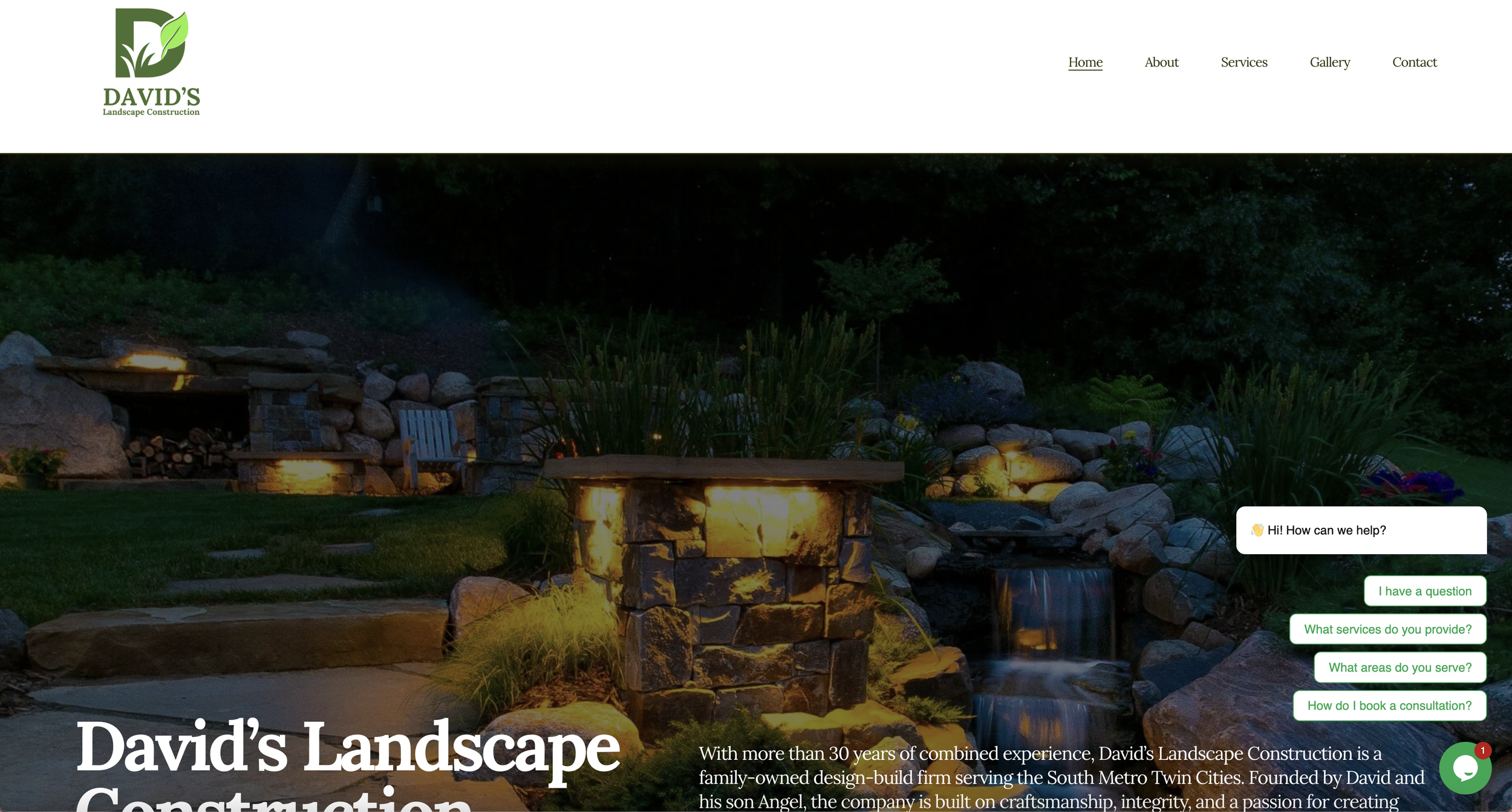 Nighttime outdoor landscape with a lit stone fireplace, wooden benches, large rocks, lush plants, and a dark forest in the background.
