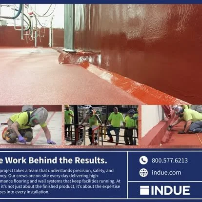 Workers finishing a painted curb along a sidewalk, one worker kneeling and one lying down, with safety gear and high-visibility clothing.