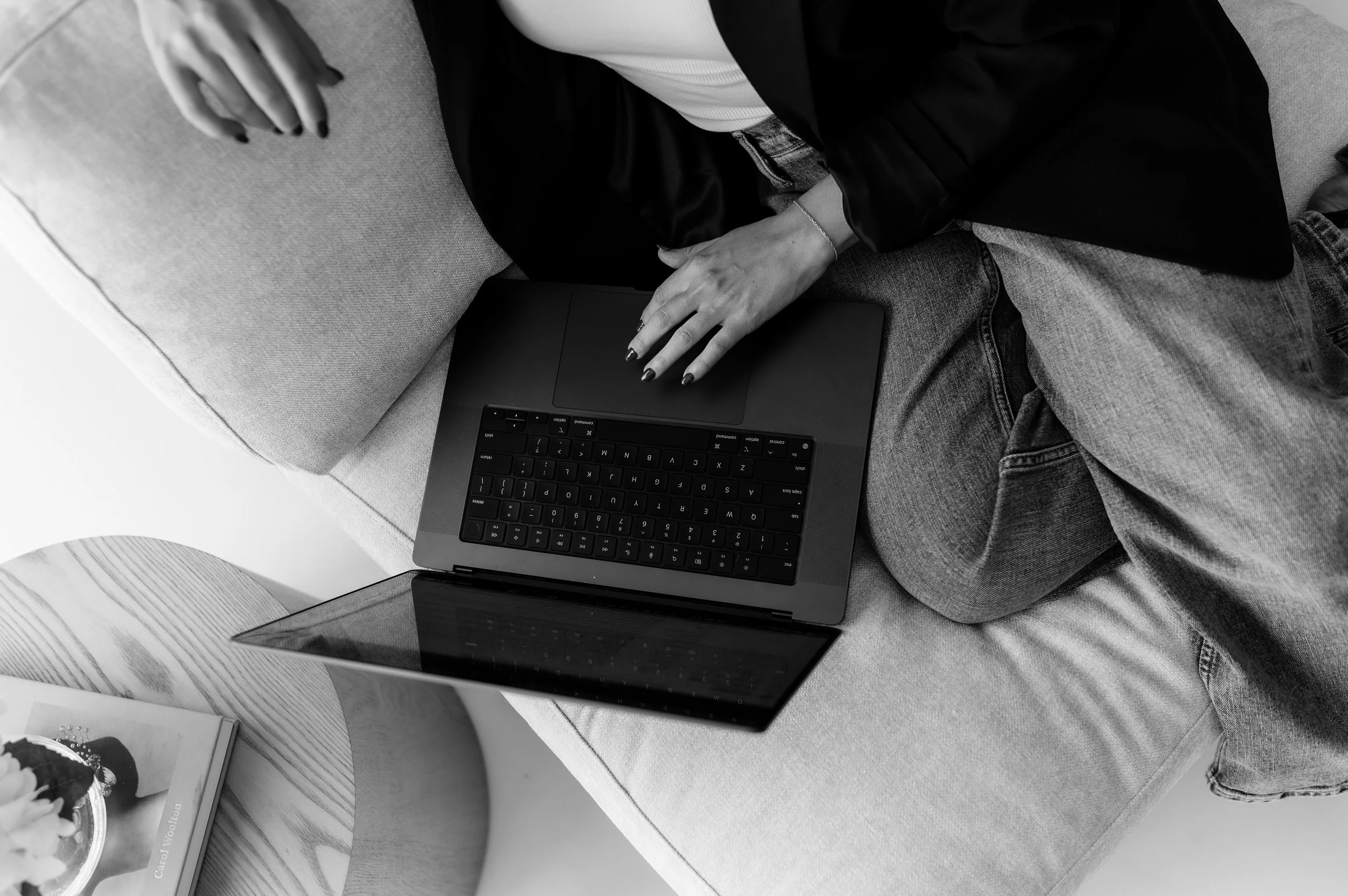 Person using a MacBook Pro and holding a cellphone, with Facebook page open on the laptop screen