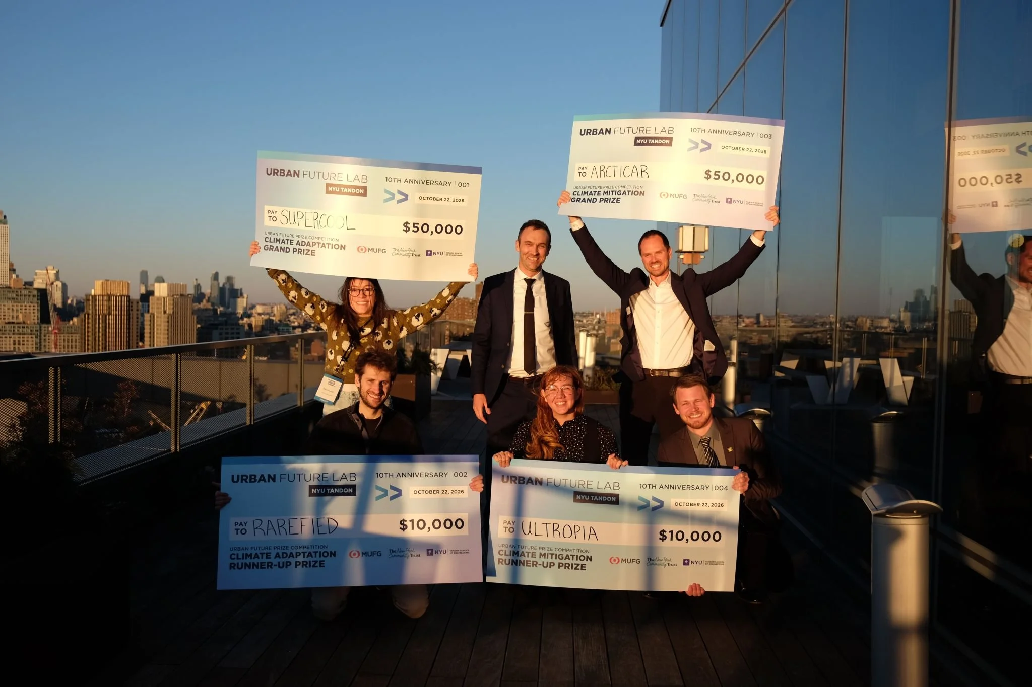 The winners of the prizes at the Urban Future Prize Summit, holding their prize checks up in the air.