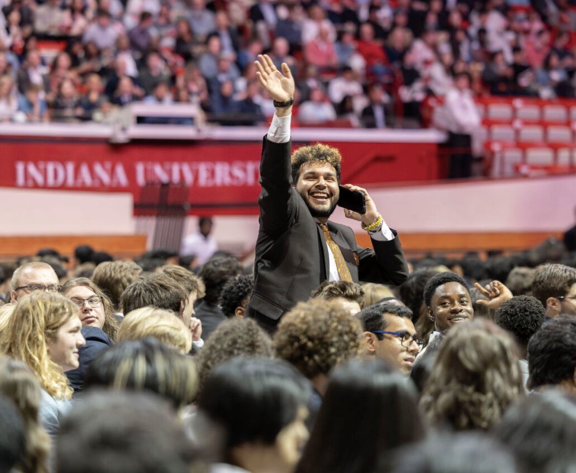 Students wave to friends and family during graduation.