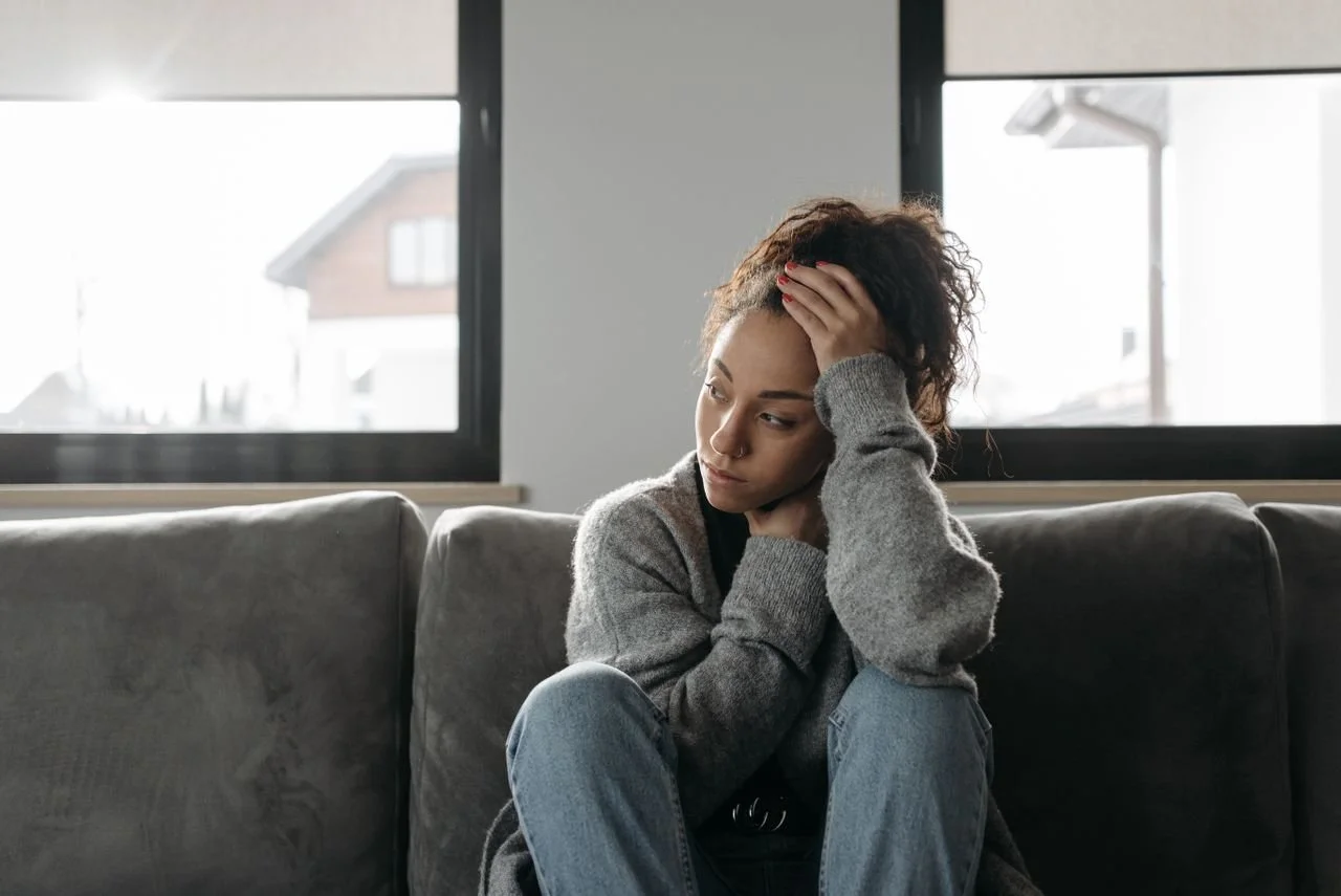 woman-in-gray-sweater-and-blue-denim-jeans-sitting-on-gray-couch