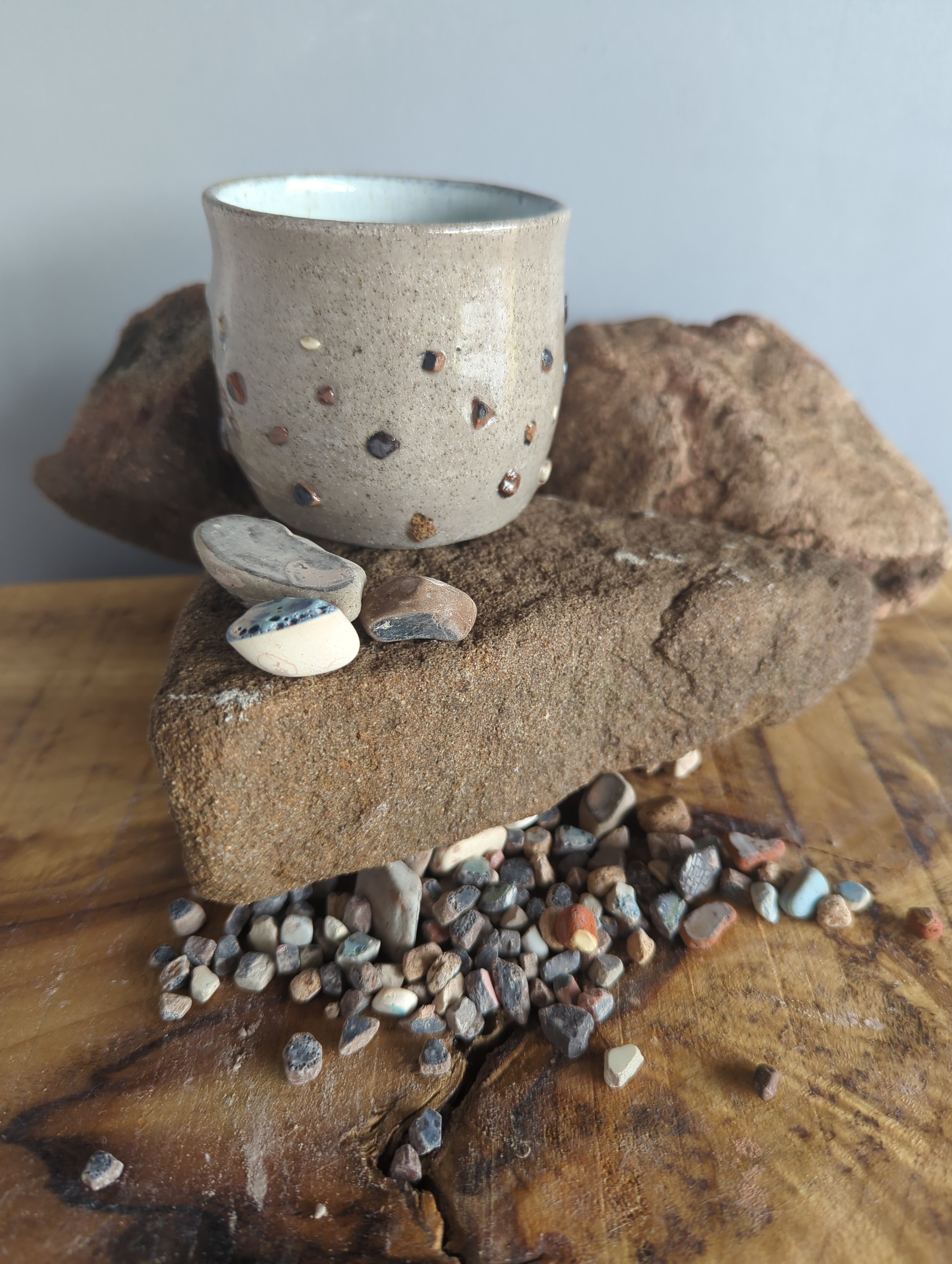 Handcrafted ceramic cup on rocks with small stones scattered