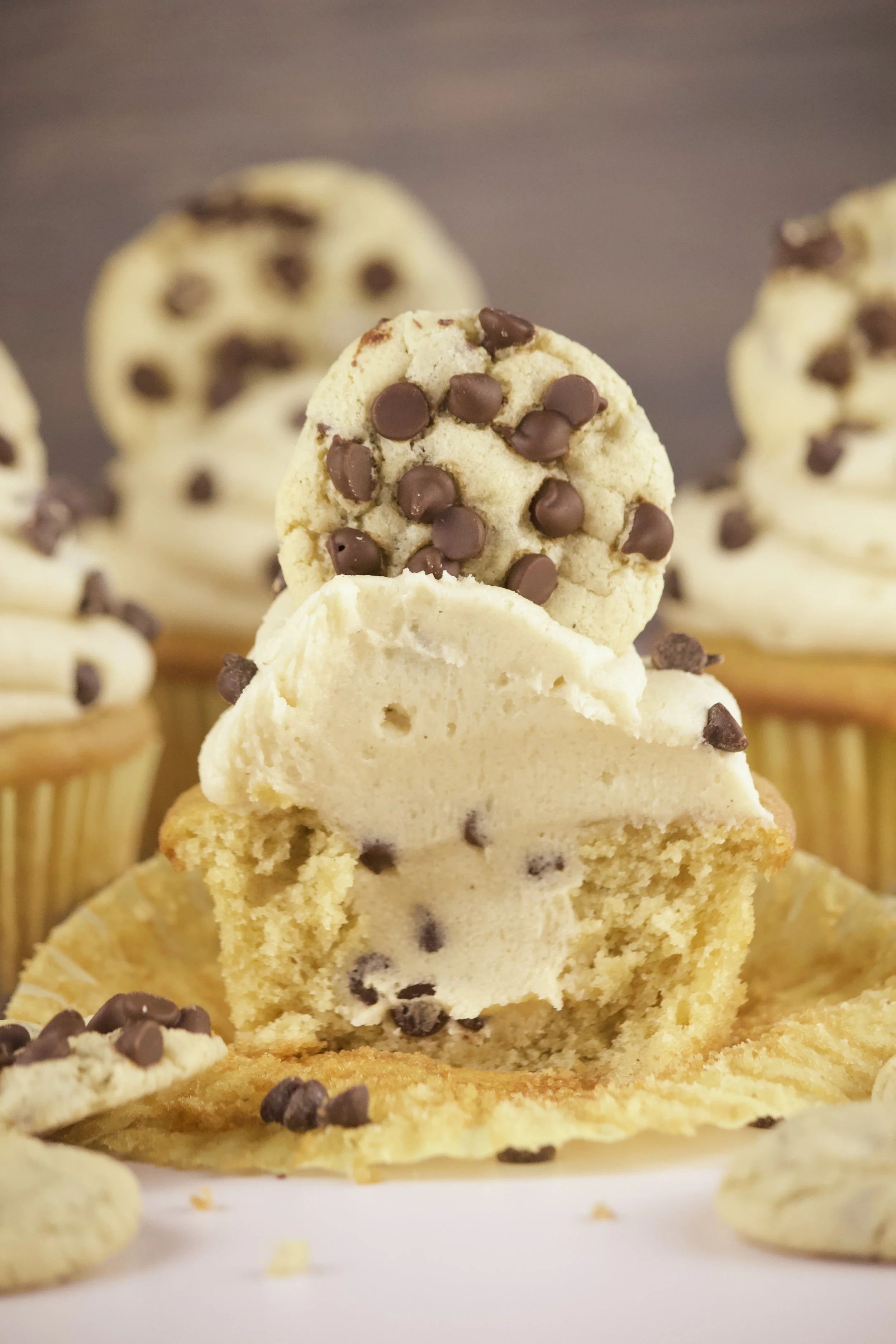 cookie dough cupcakes filled with cookie dough and topped with a chocolate chip cookie