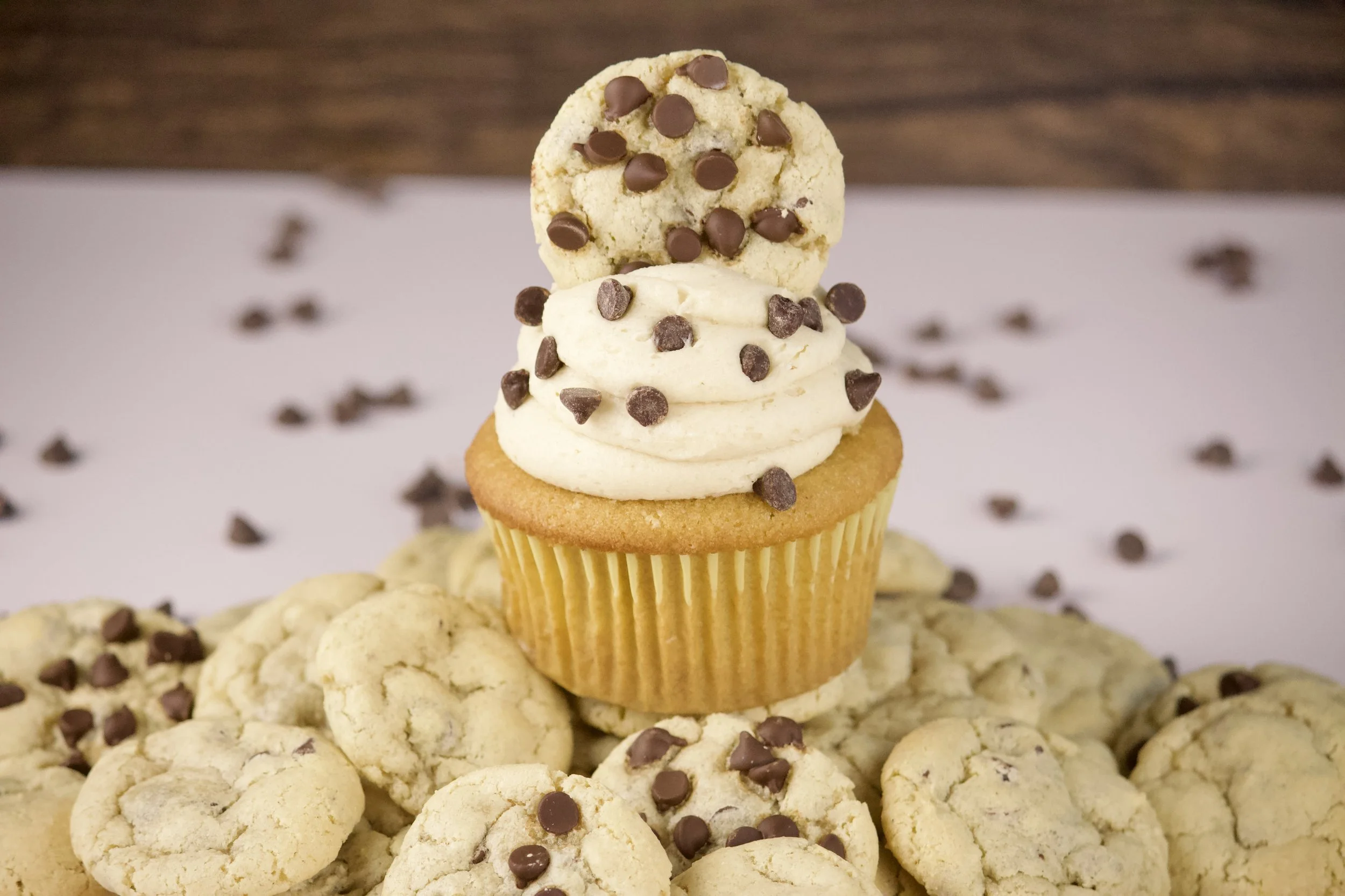 chocolate chip cookie dough cupcake on top of a mountain of chocolate chip cookies