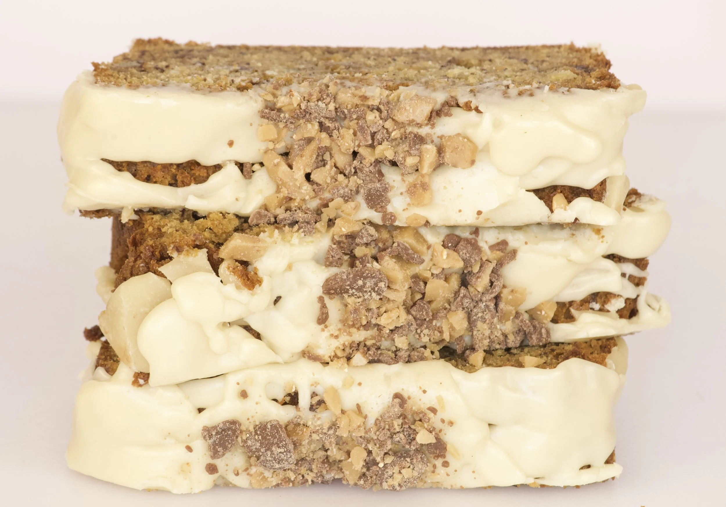 stack of banana bread sliced with icing and toffee chunks