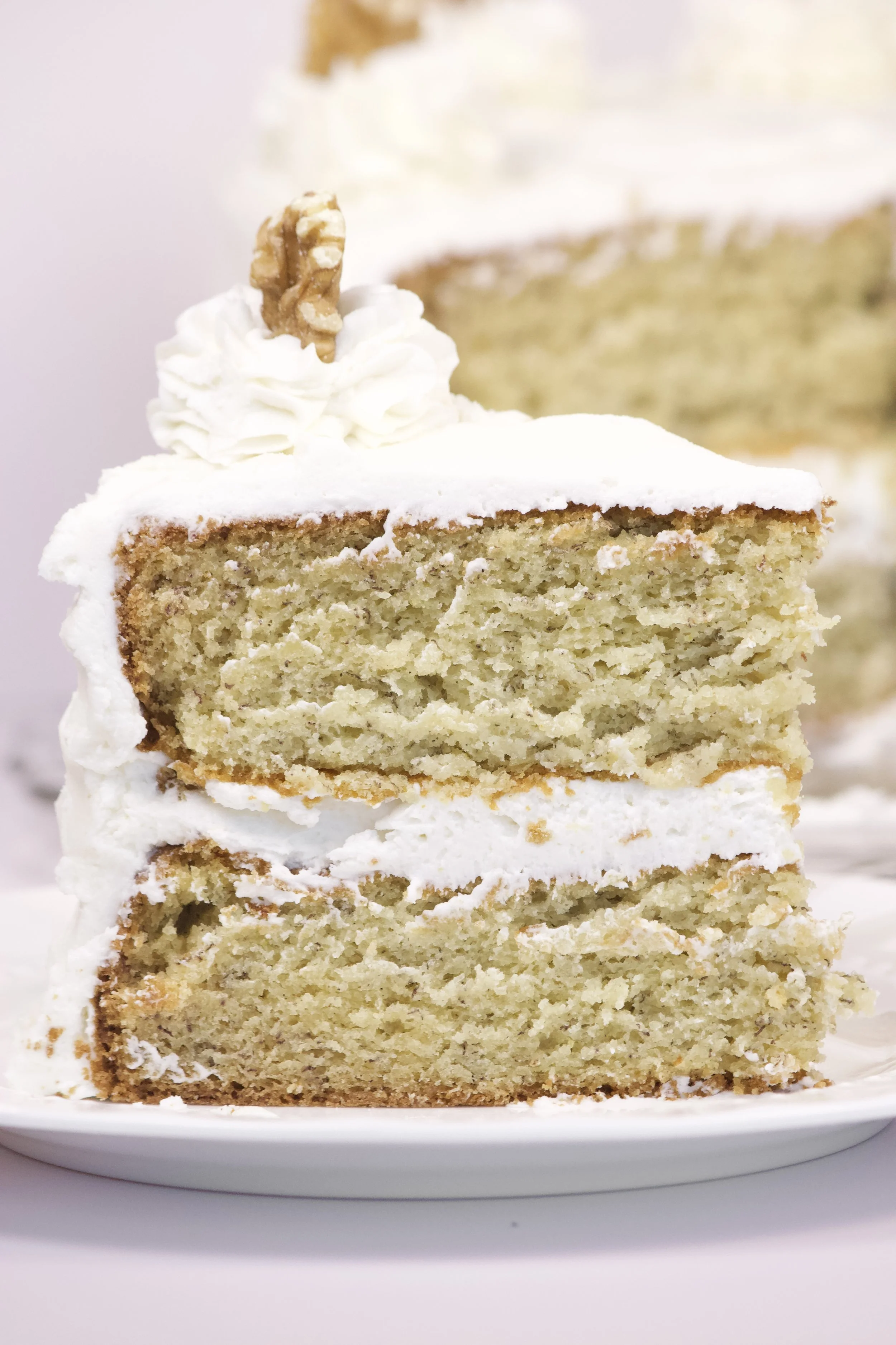 slice of banana cake with vanilla buttercream and a walnut