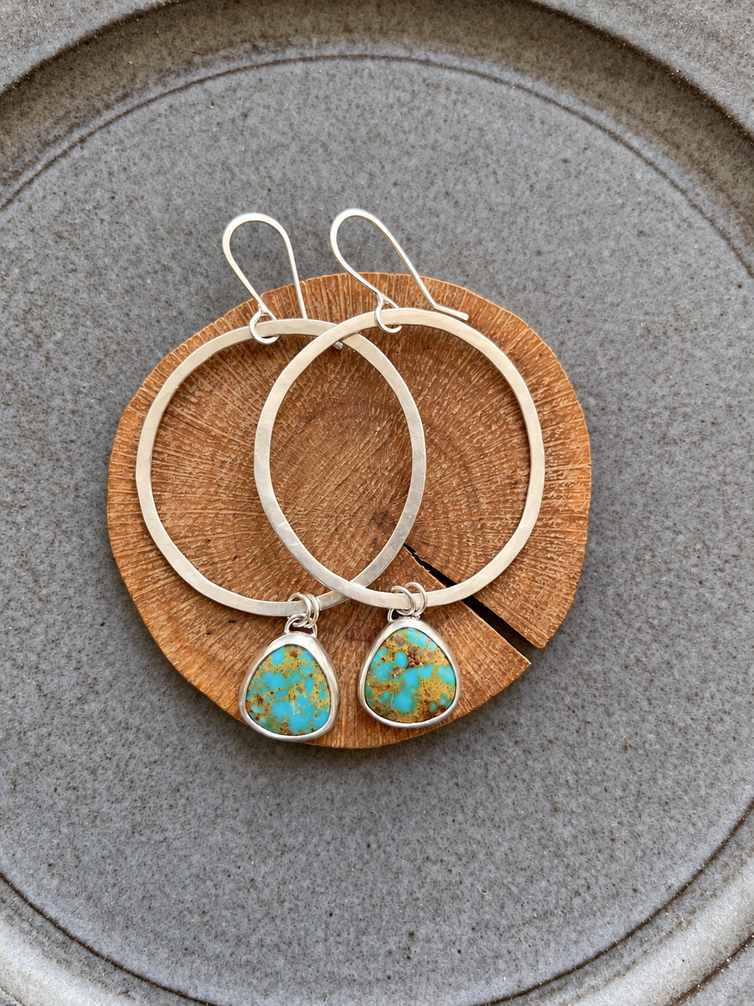 Overlapping turquoise hoops on natural wood.png