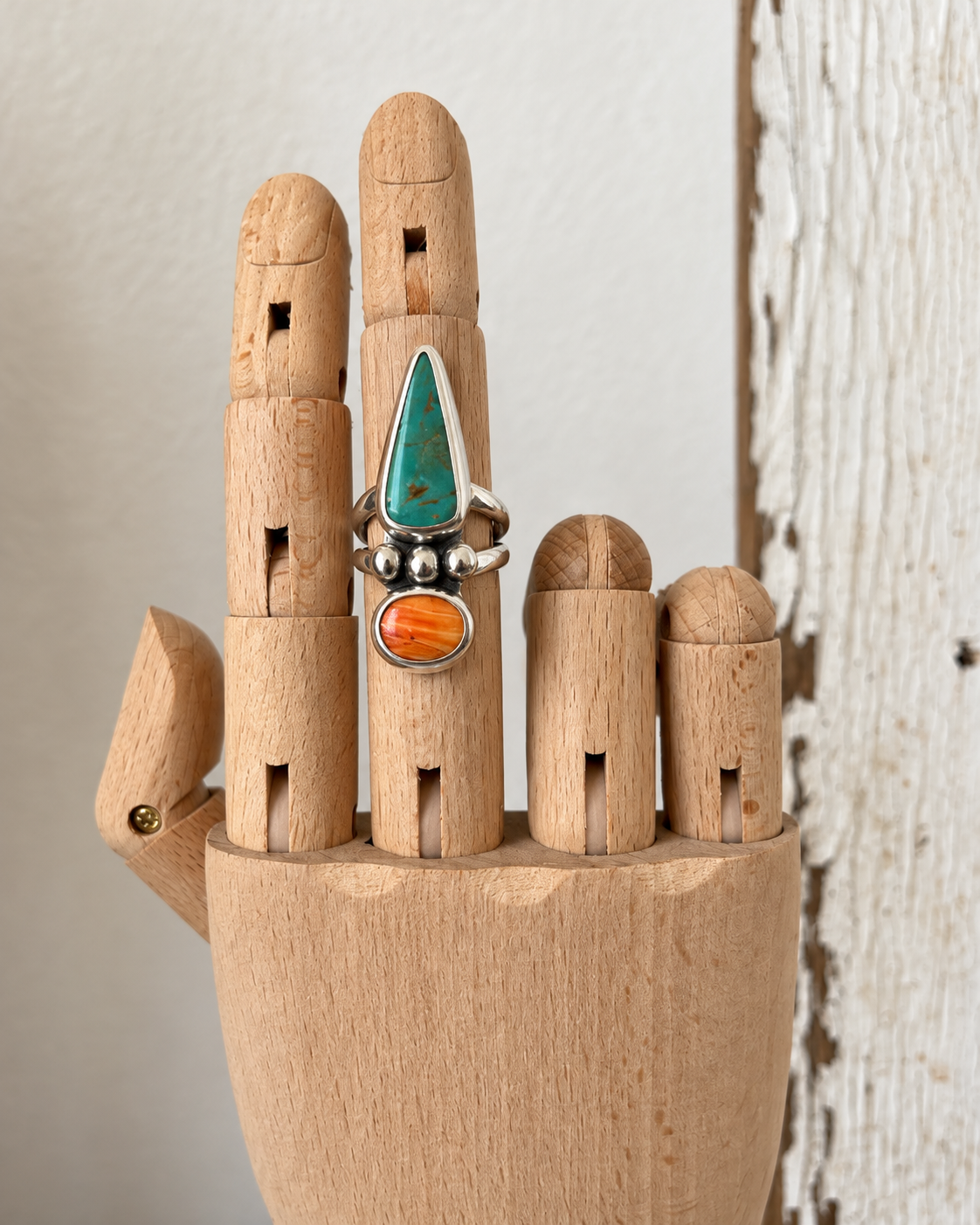 Handmade turquoise ring on wooden hand.png