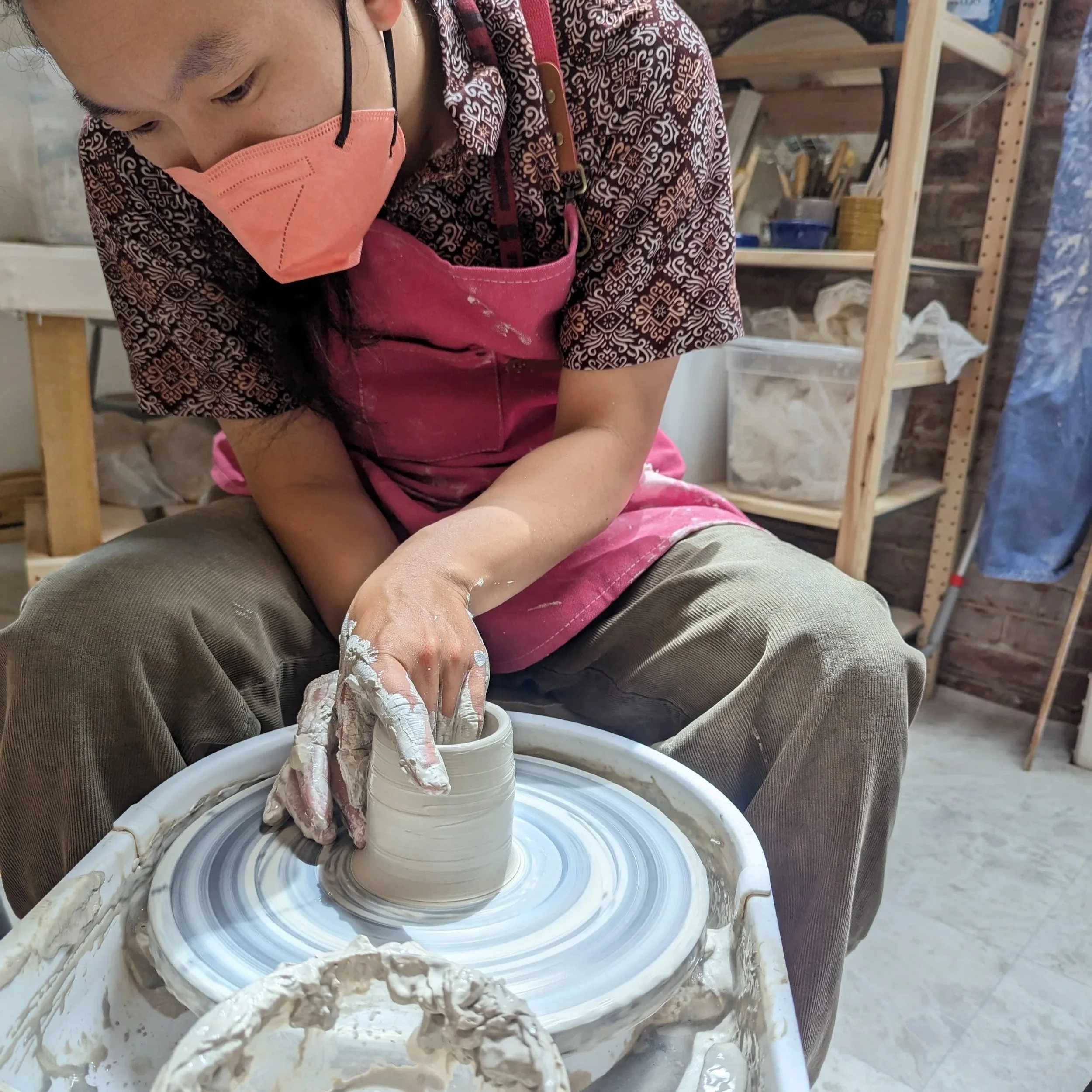 Individual pottery student playing on the wheel