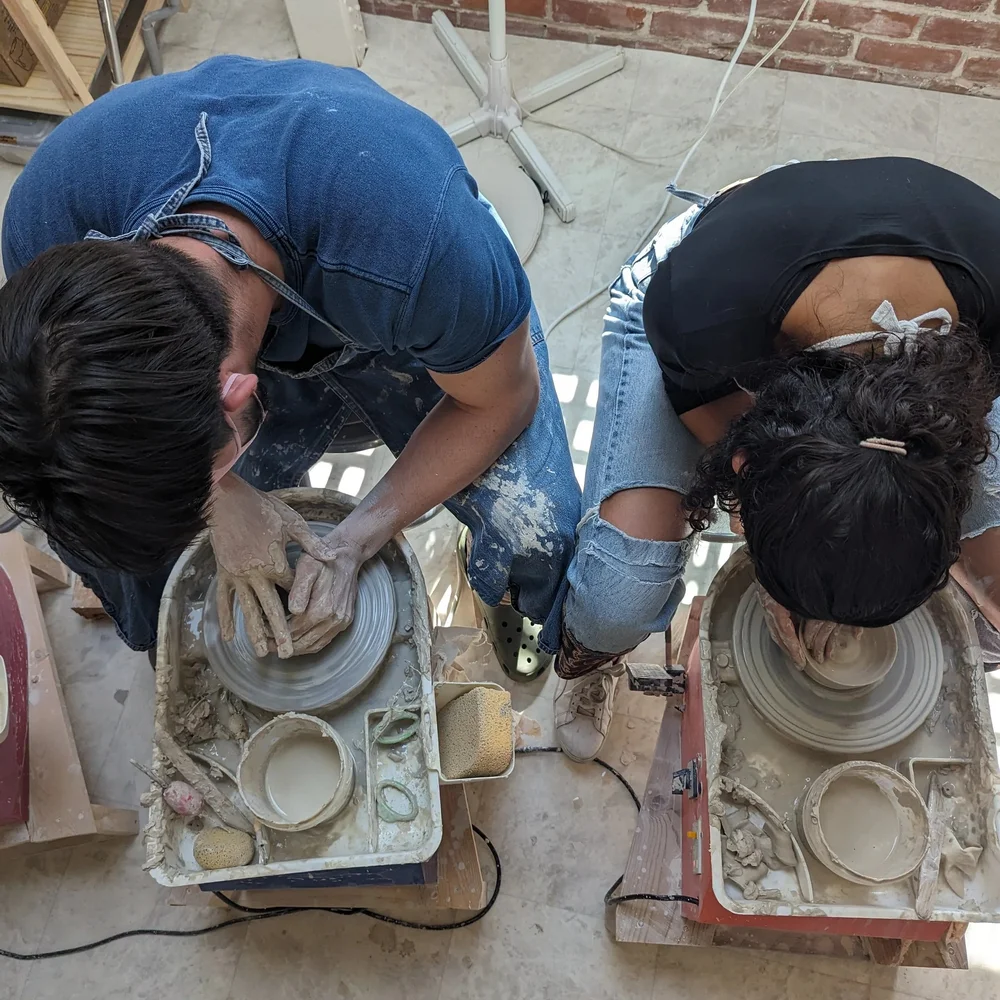 Two new pottery students playing with clay one time pottery class