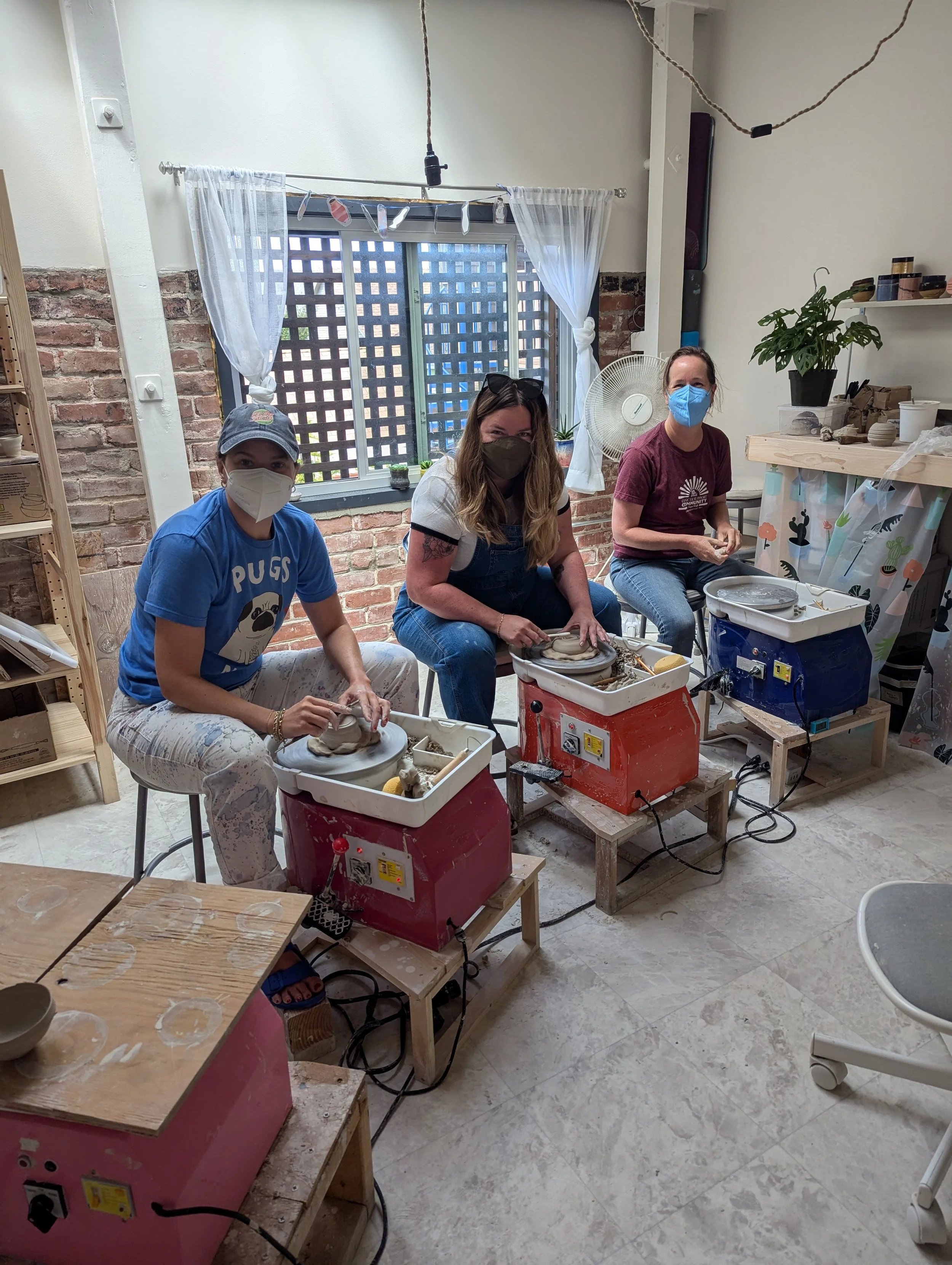  A group of masked students throwing on the potter’s wheel in a beginner studio in Oakland, CA 