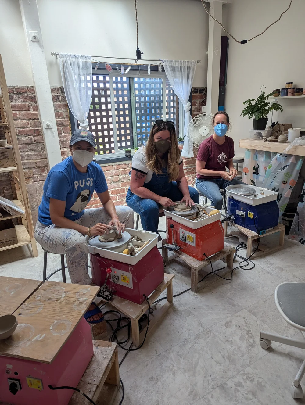  A group of masked students throwing on the potter’s wheel in a beginner studio in Oakland, CA 
