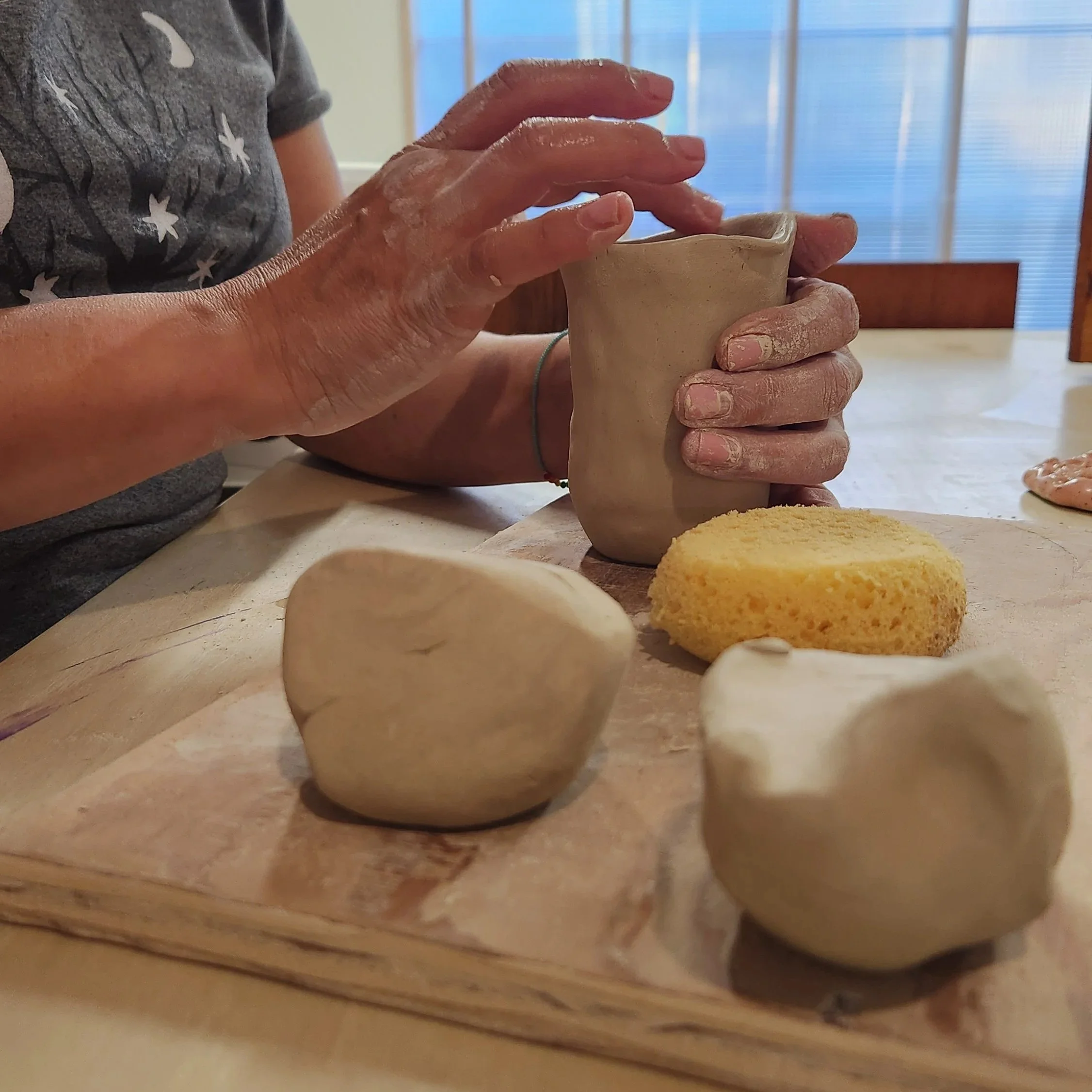 An intermediate student crafts a handbuilt clay vase at a ceramics studio 
