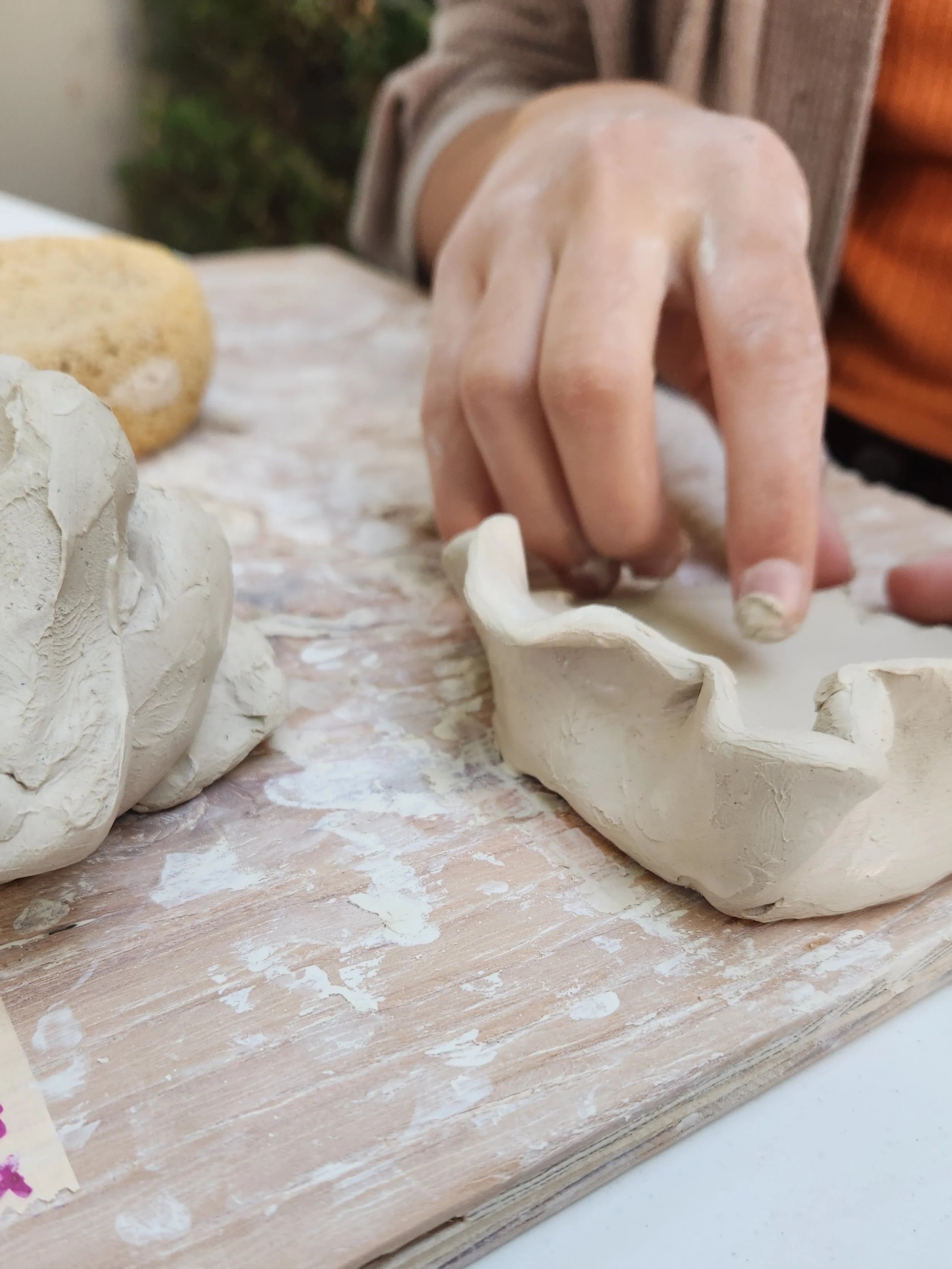 An artist shapes clay with their hands, creating an organic form