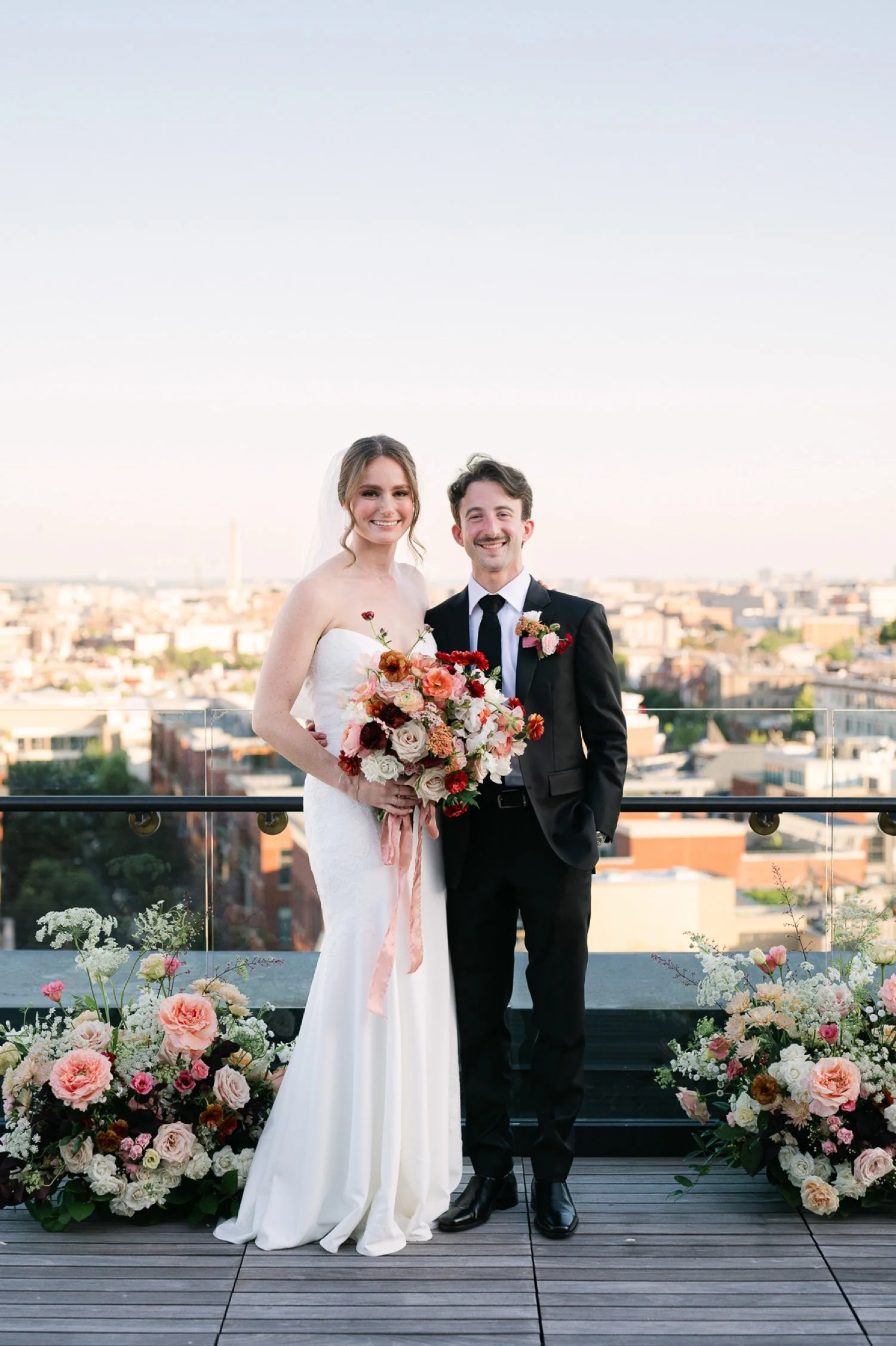 bride-and-groom-smile-between-ground-floral-arrangements-on-monument-suite-rooftop-.jpg.jpg