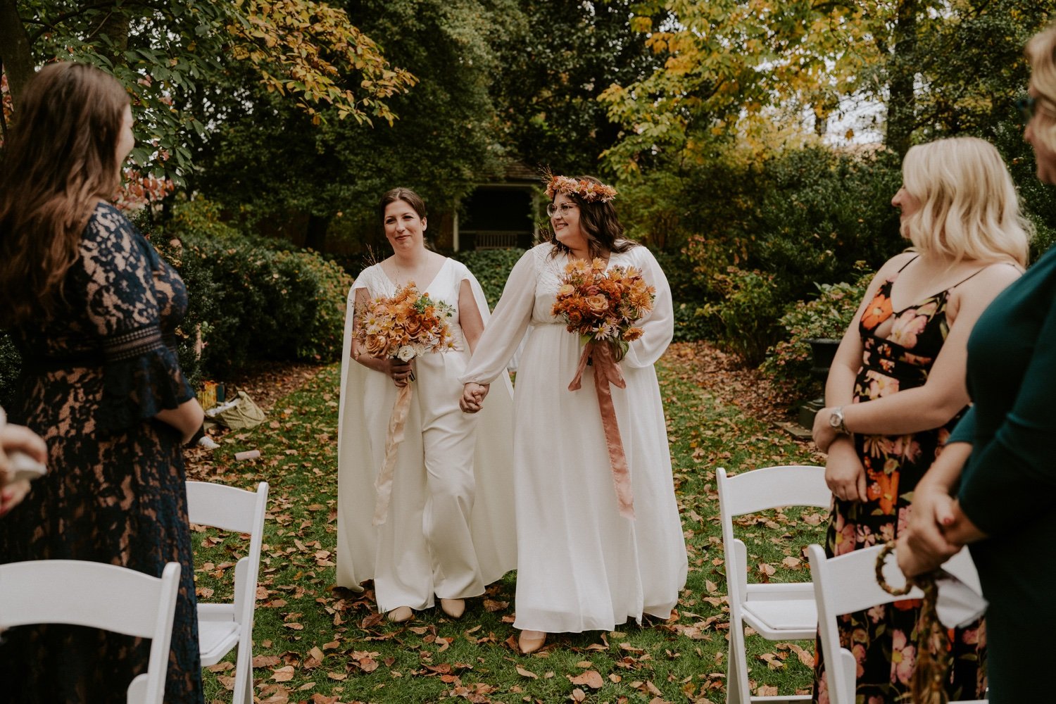 two-brides-holding-fall-colored-bouquets-walking-down-aisle-at-tudor-place-historic-house-and-garden-.jpg.jpg