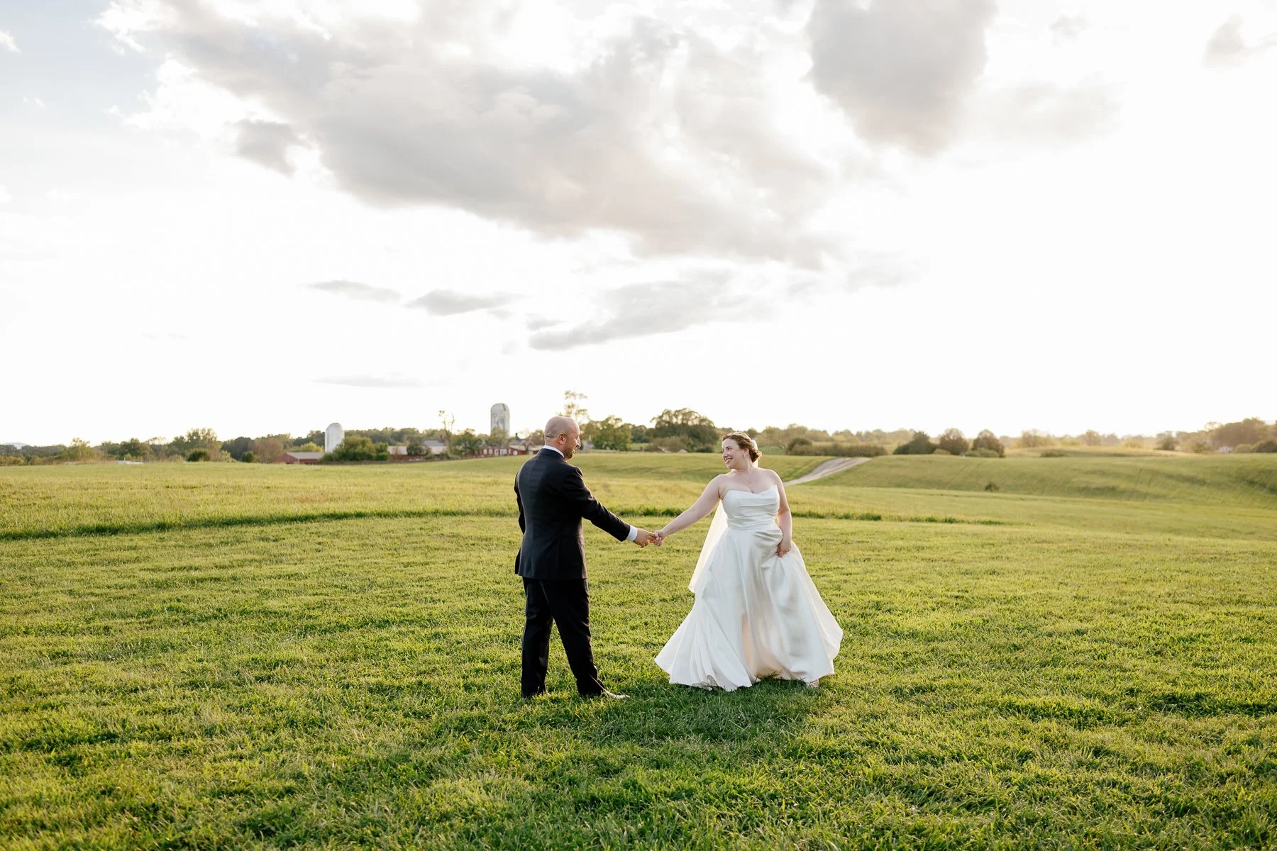  Couple walking through the hayfield at Goodstone Inn at sunset 