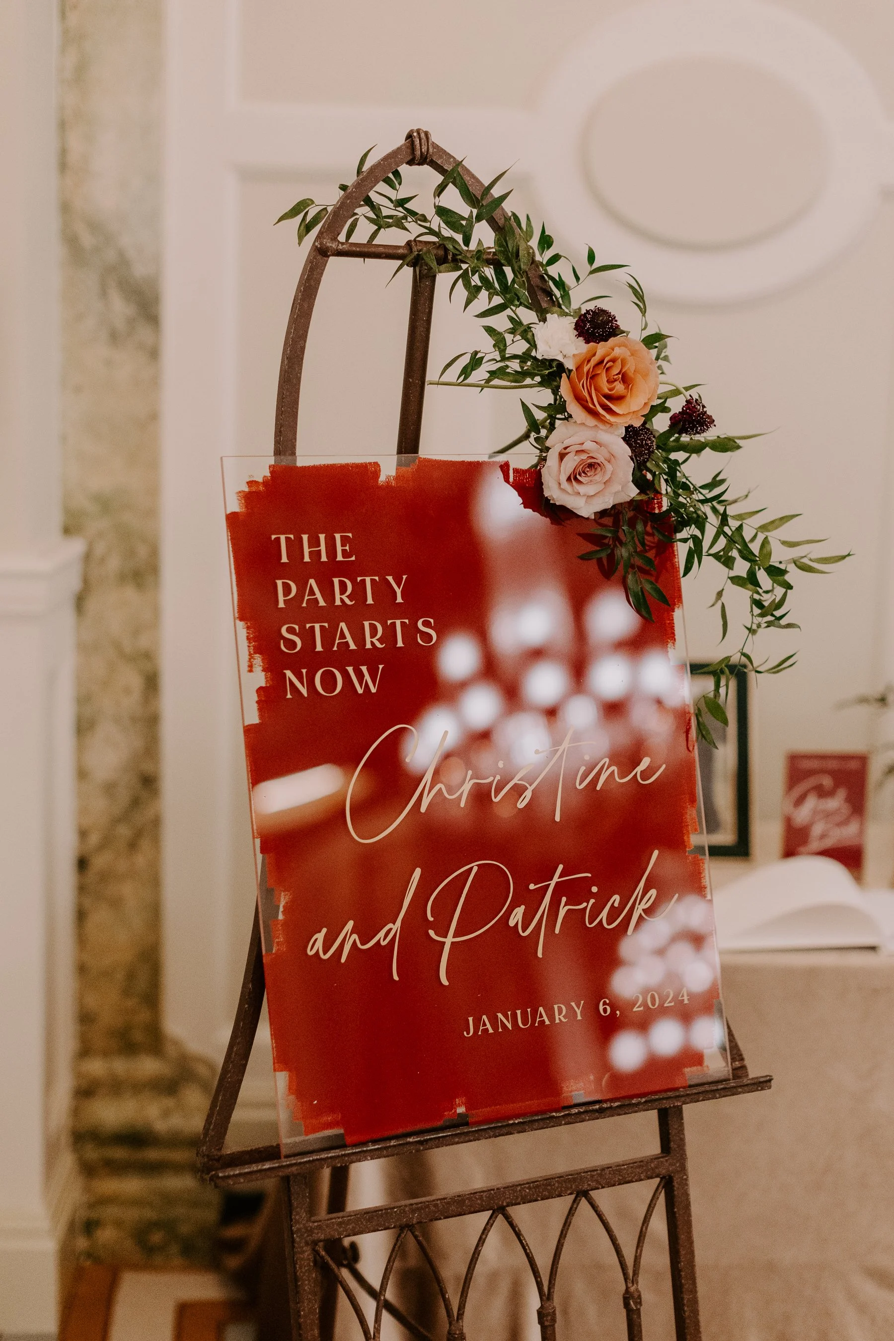 Welcome sign at DC small, intimate wedding that says The Party Starts Now with the couples name and wedding date on a red sign. A pink rose bundle is on the right corner.