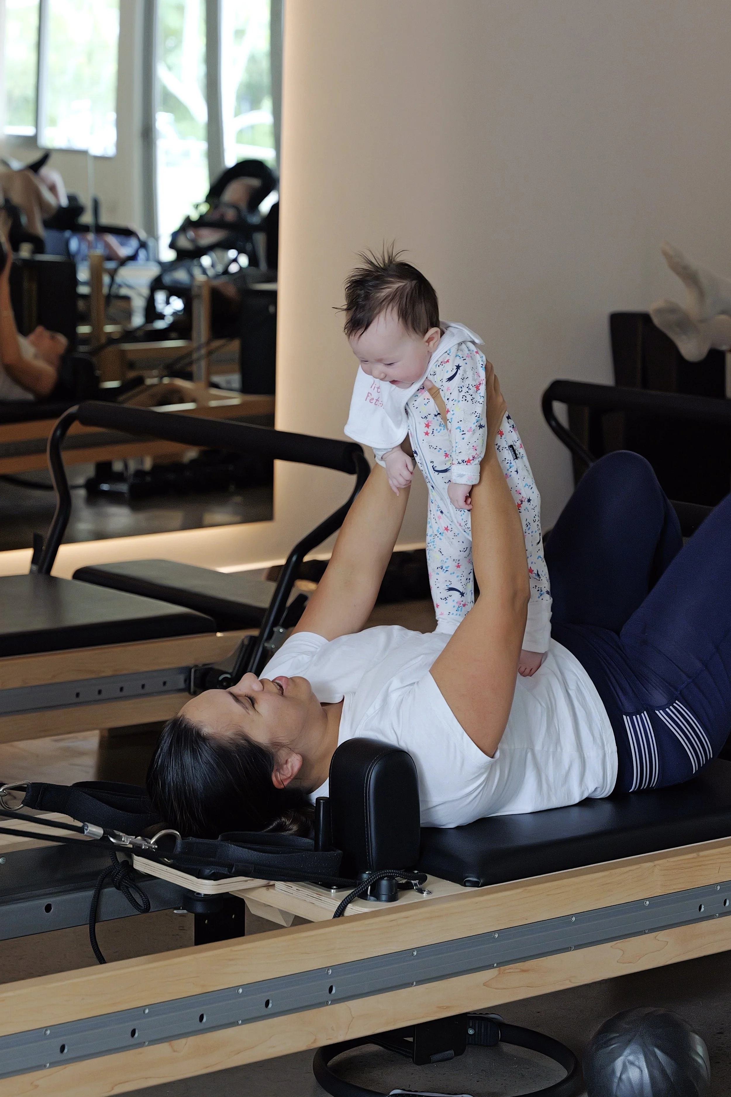 Mum using reformer machine during postnatal Pilates class