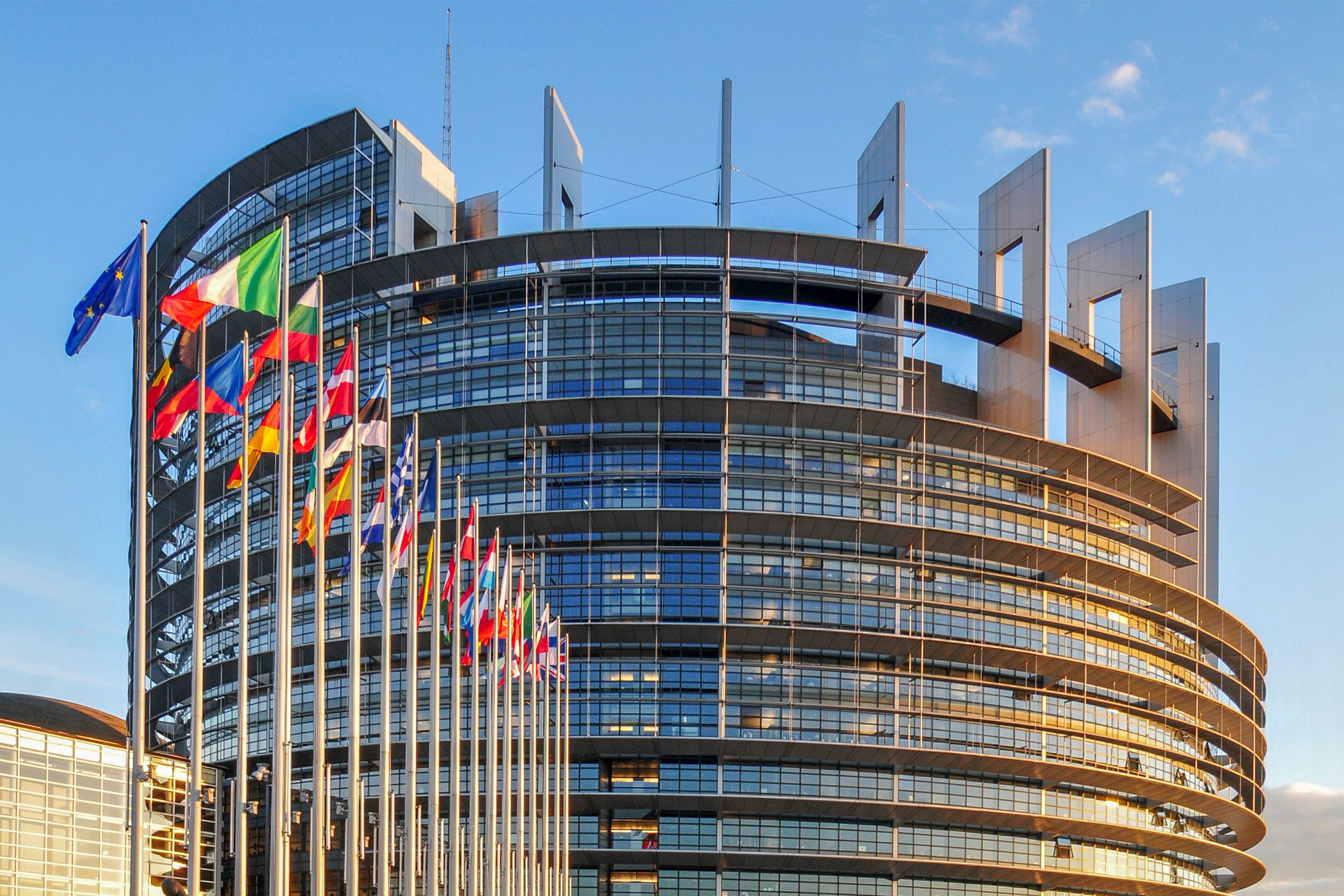 Euroopan parlamenttiin liittyvä pyöreä rakennus, jonka edustalla eri maiden lippuja