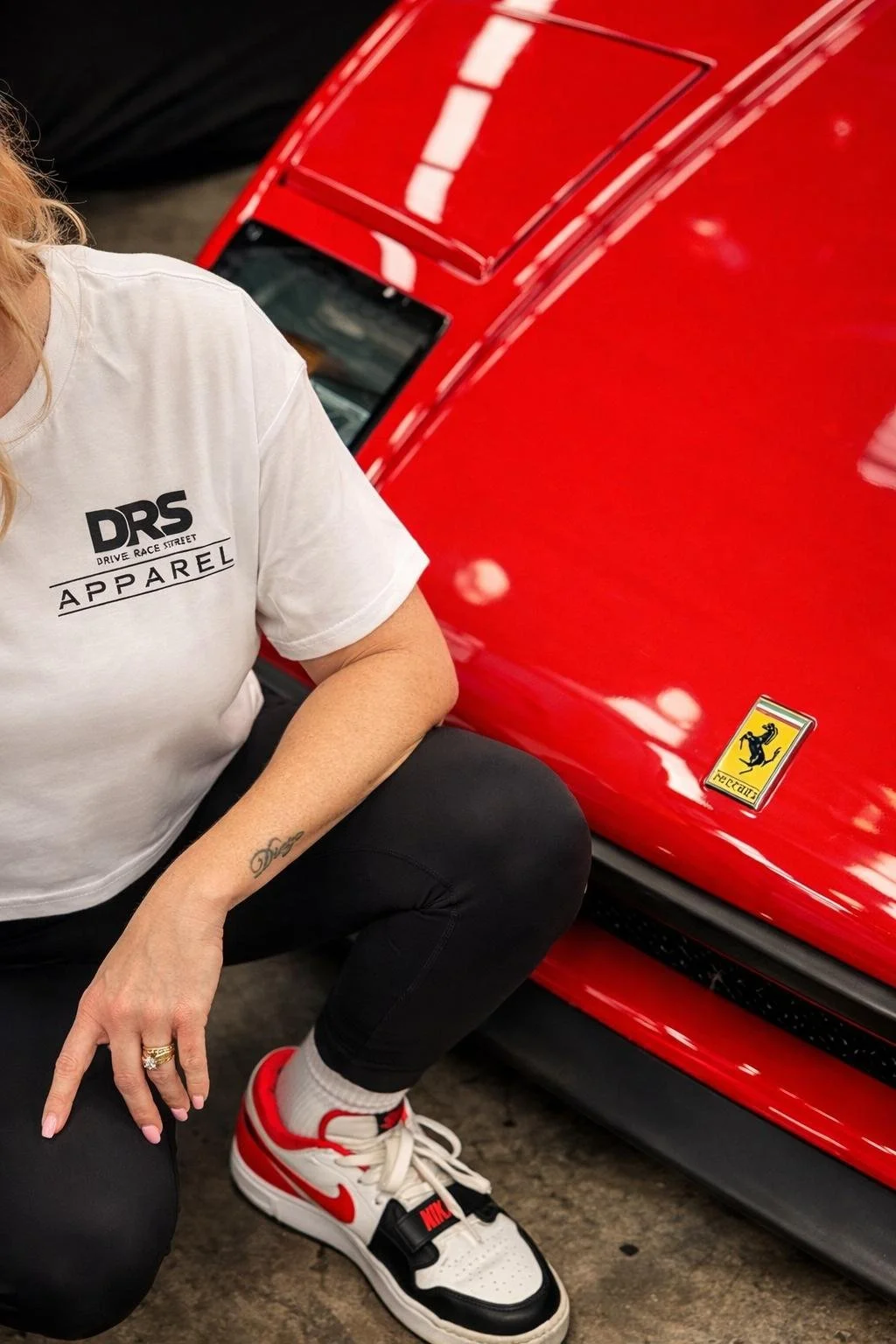 A close up shot of the black logo from DRS Apparel, next to the badge of a Ferrari F40. 