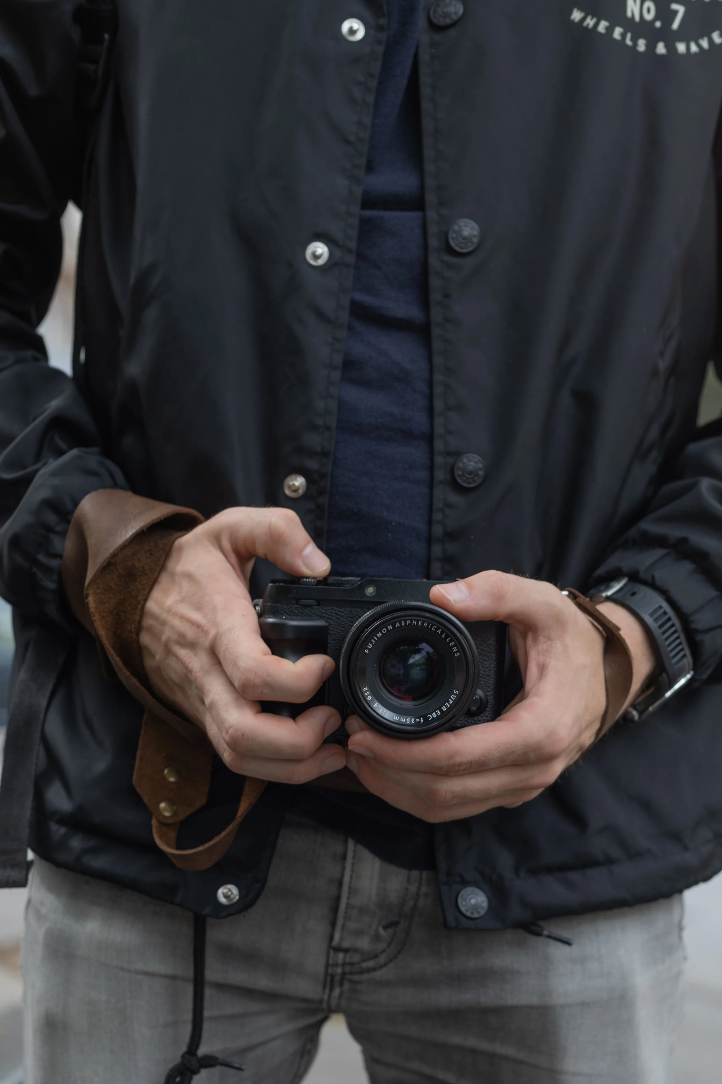 Person wearing a black jacket holding a camera.
