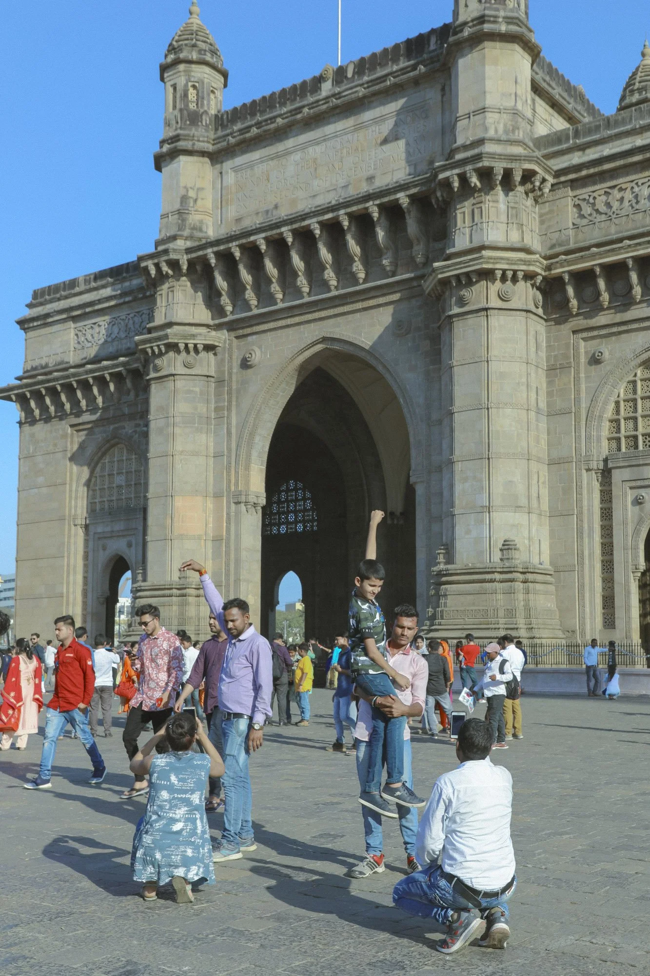 Group of people gathered in front of a historic monument on a sunny day.