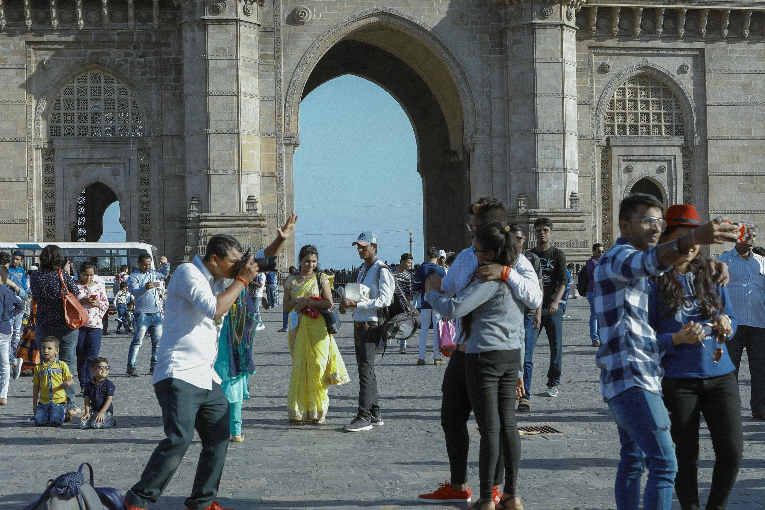 People taking photos and socializing in front of the India Gate monument in New Delhi, India.