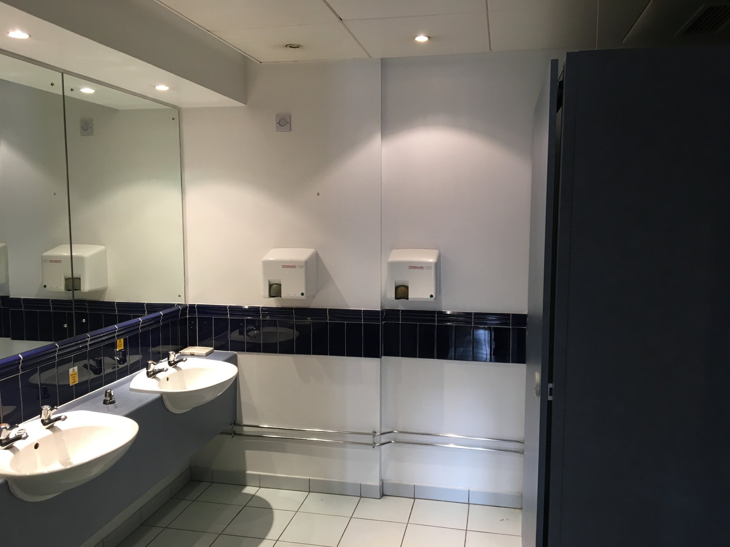 Public restroom with sinks, mirrors, and soap dispensers, part of an office fit-out by GM Projects.