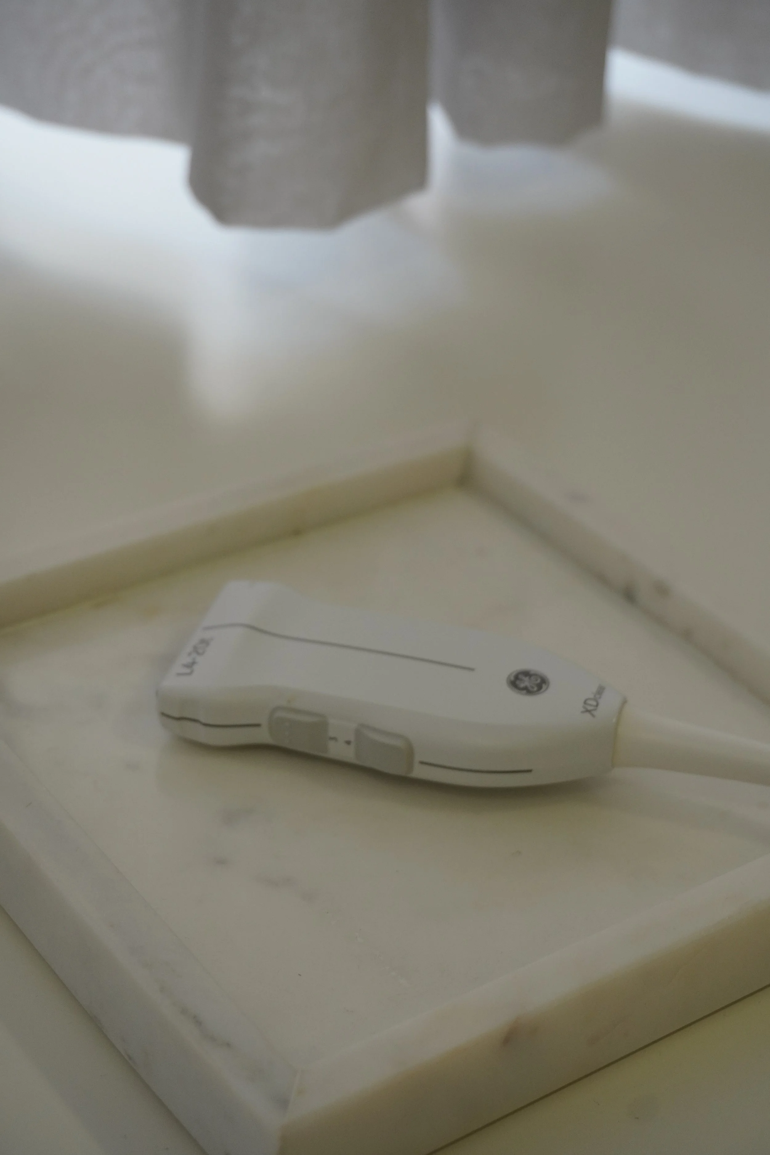 Ein Ultraschallgerät liegt auf einer weißen Marmorablage in einem medizinischen Umfeld.