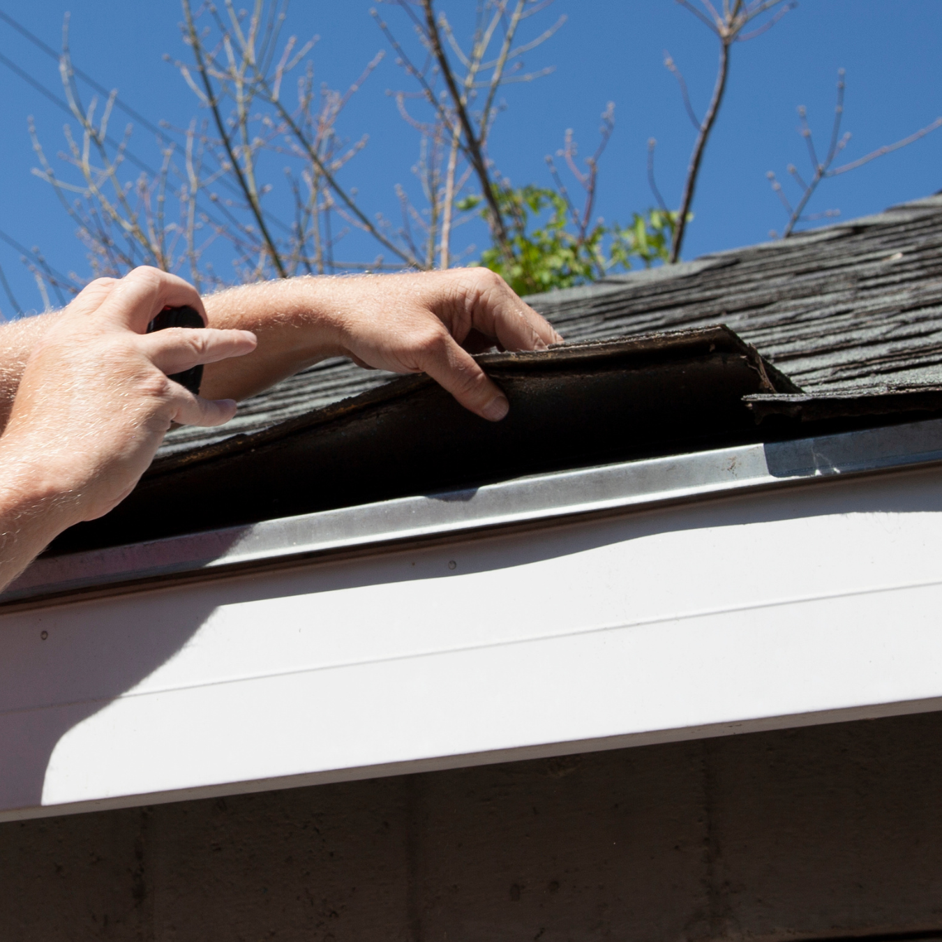 Professional roofer checking residential roof for leak damage