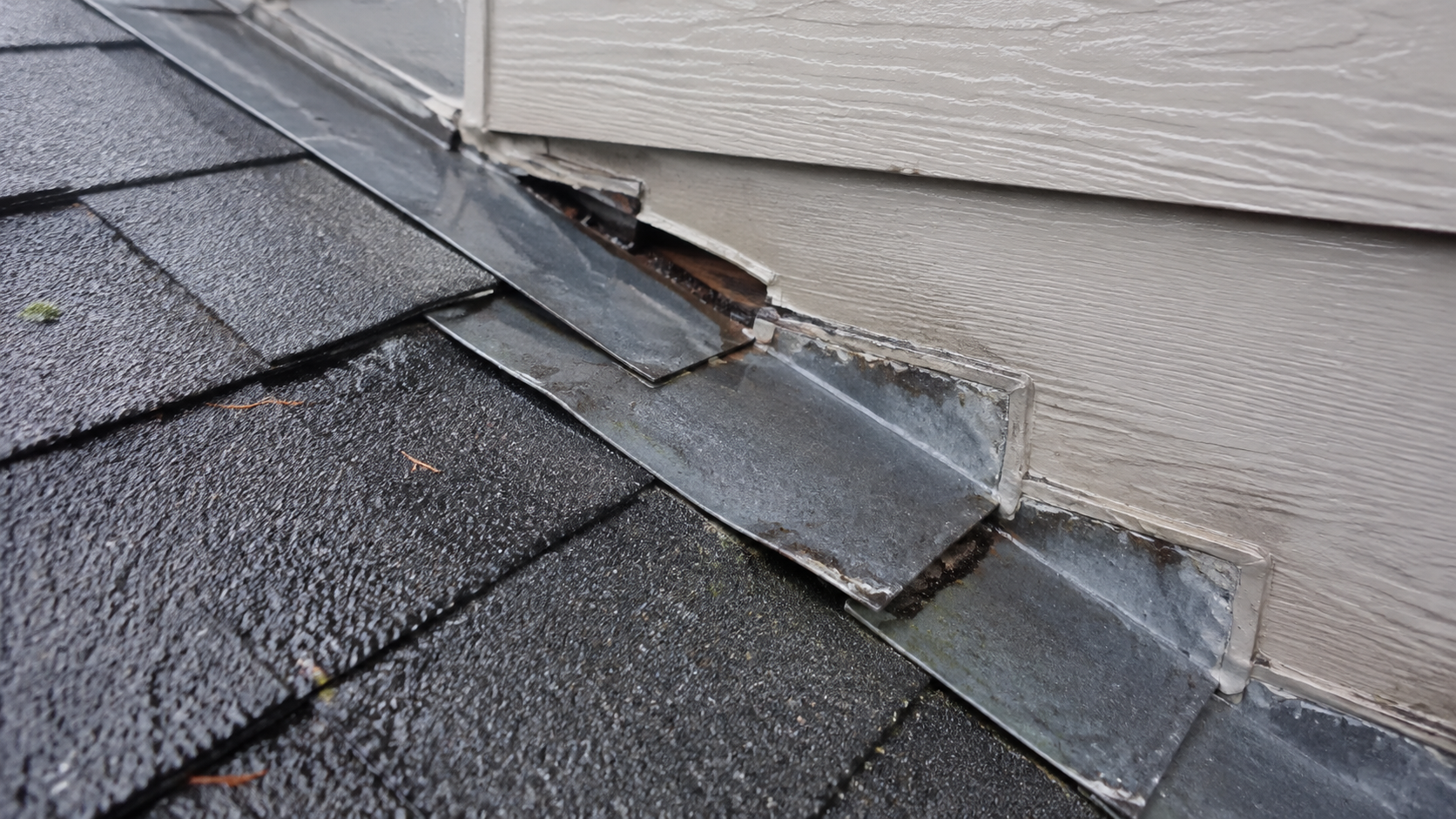 Damaged metal roof flashing pulled away from the wall, leaving a gap that requires repair.