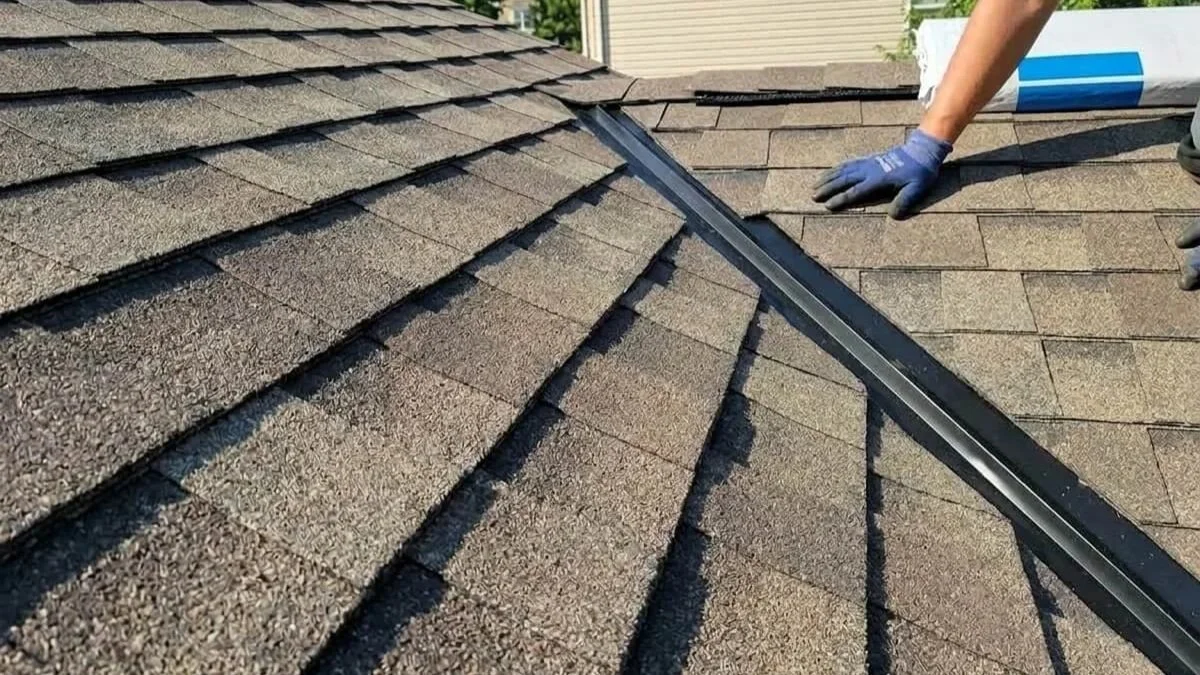 Roofer's gloved hand installing black hip and ridge flashing over synthetic underlayment during a Maryland roof replacement.
