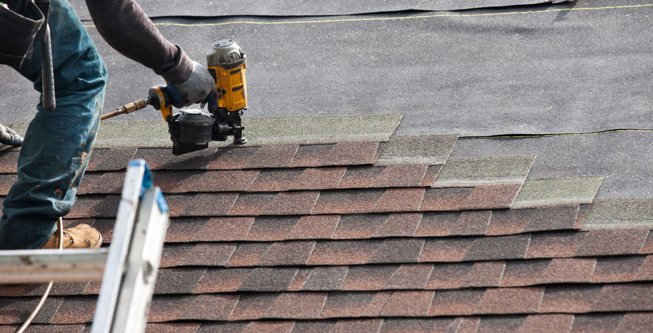 Roofer using an industrial pneumatic coil framing nailer on a roof