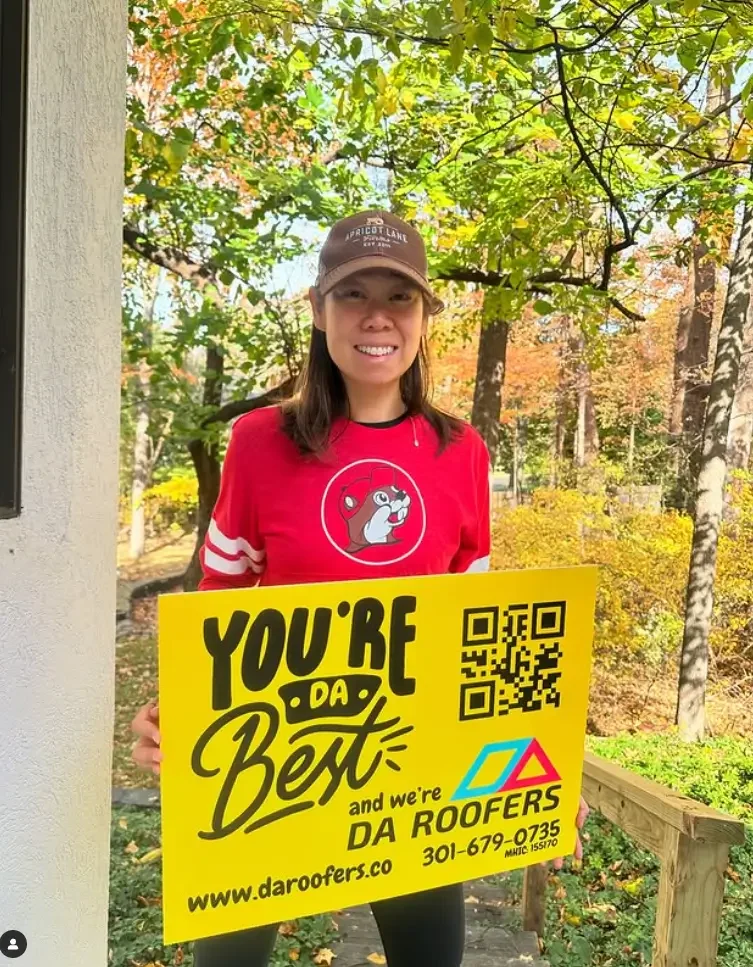 Anchi the co-owner holding a sign of DA Roofers