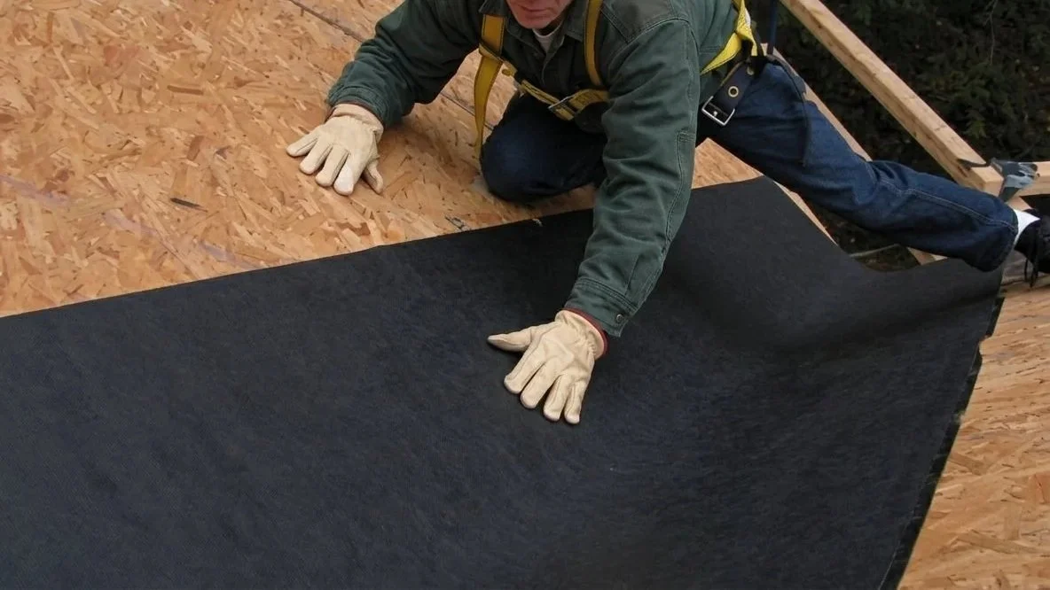 A roofer installing an ice water shield in a valley of roof