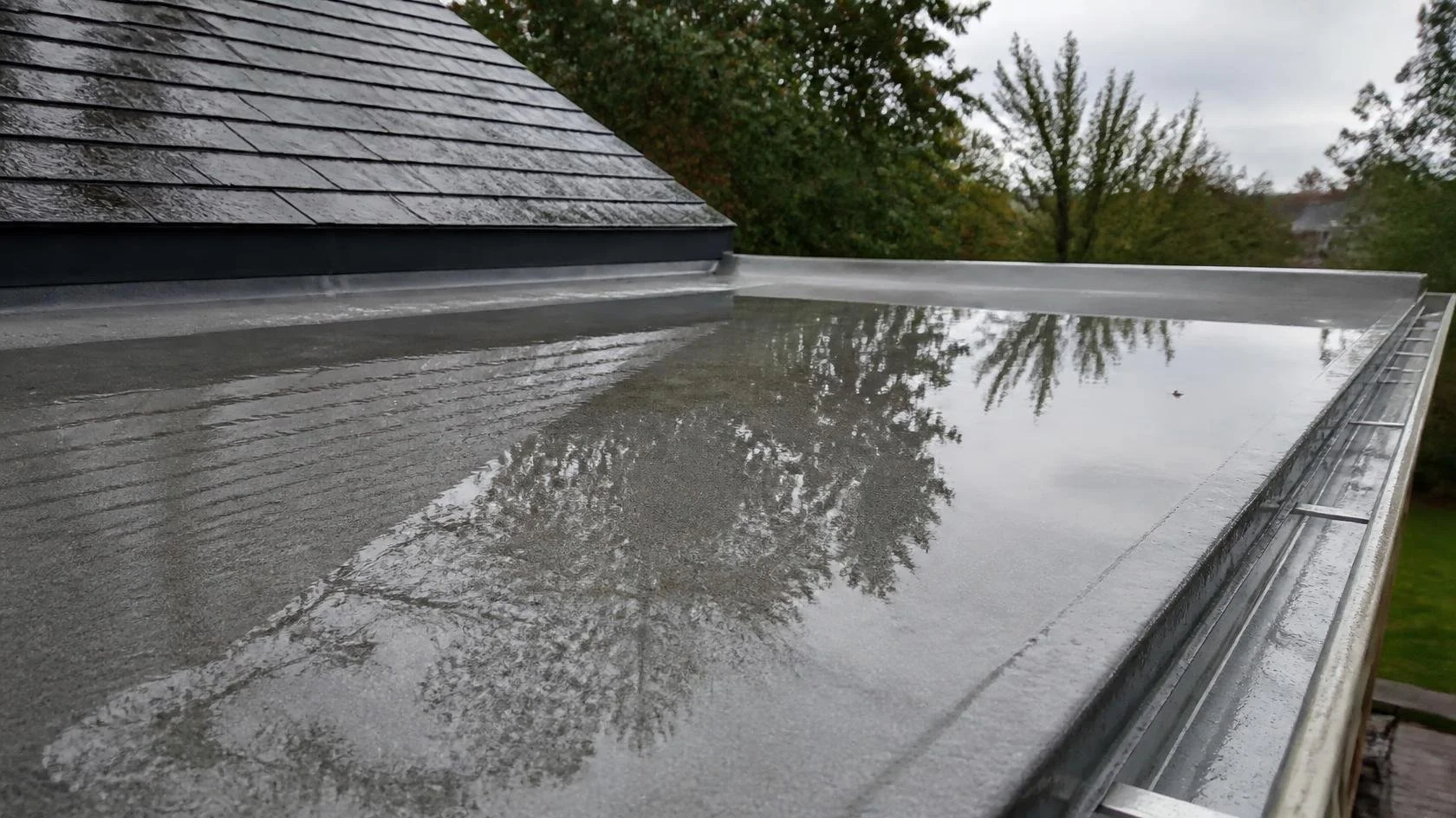 Standing water on a low-slope membrane roof after rain on a Maryland home.
