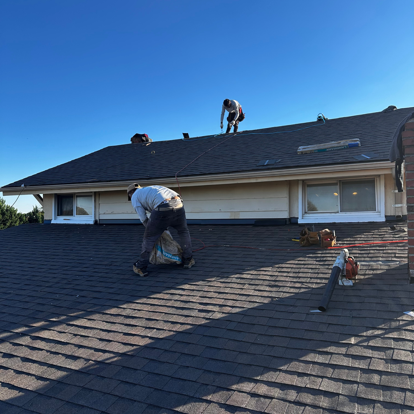 Da' Roofers cleaning up debris after roof installation in the DMV