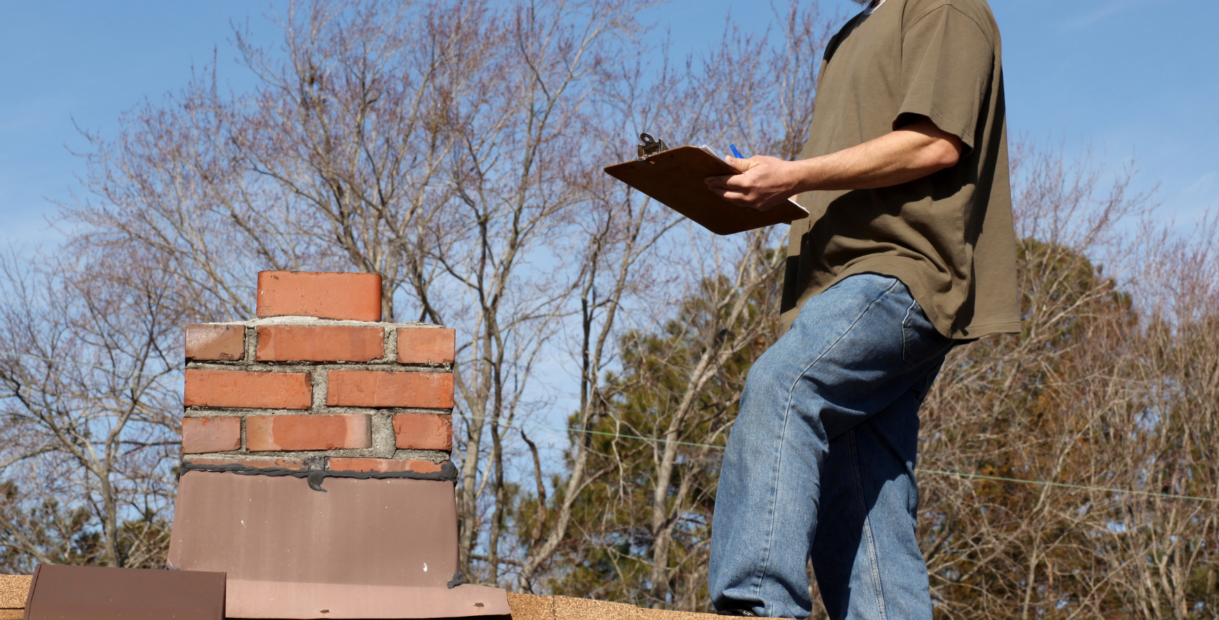 A roofer writing in his checklist while standing on a roof