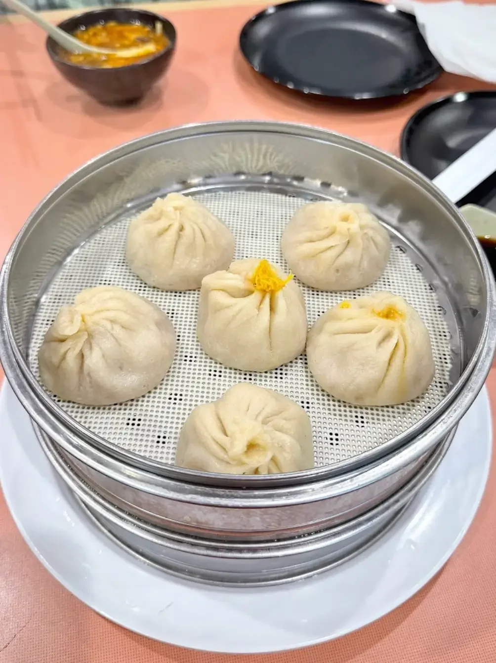 Steamed dim sum dumplings in a metal basket at a restaurant table.