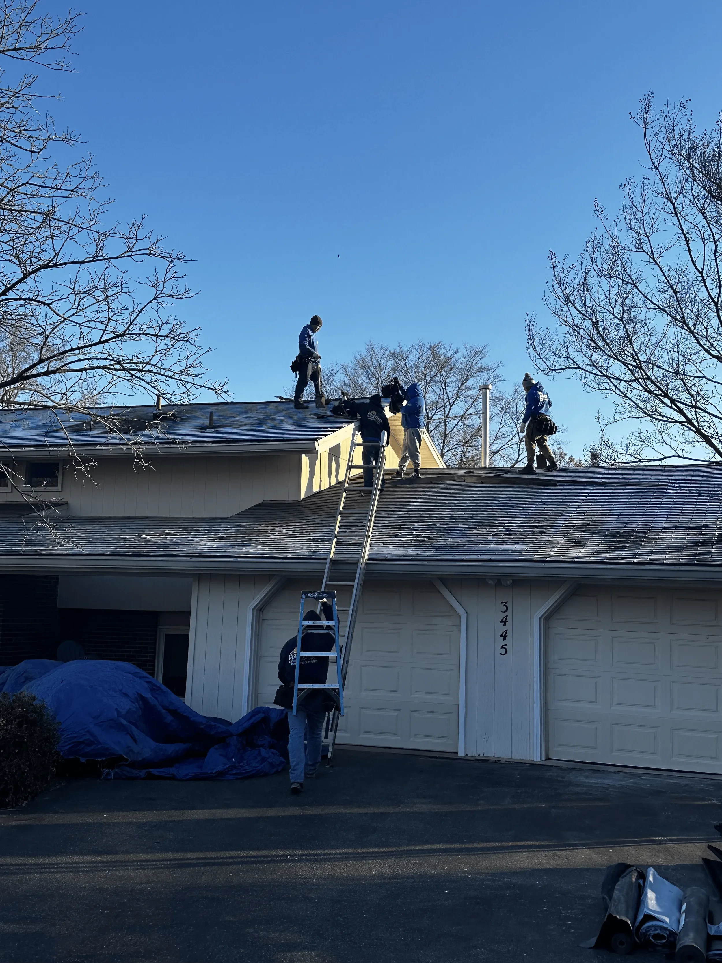 DA Roofers with a ladder working on a gray roof