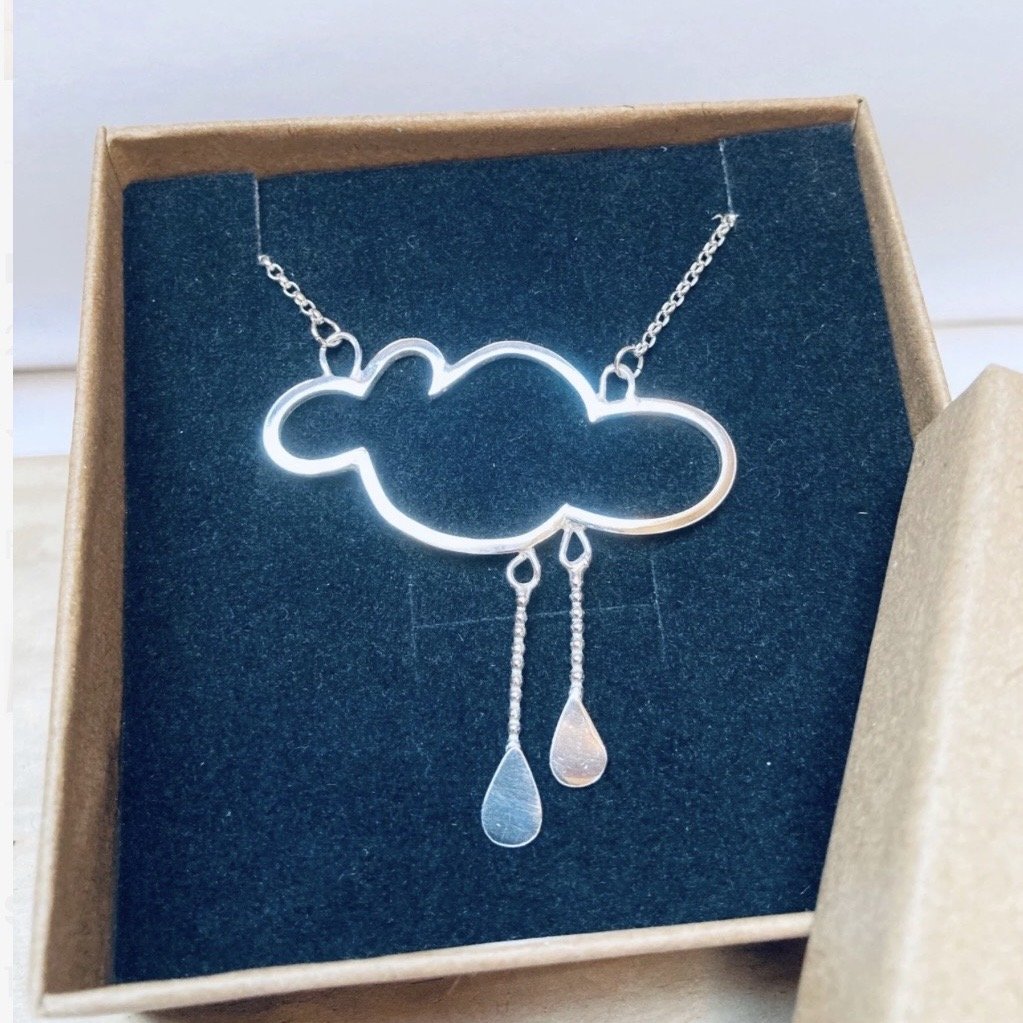 Necklace with a cloud-shaped pendant and two tear-shaped droplets hanging from it, displayed in a black jewelry box.