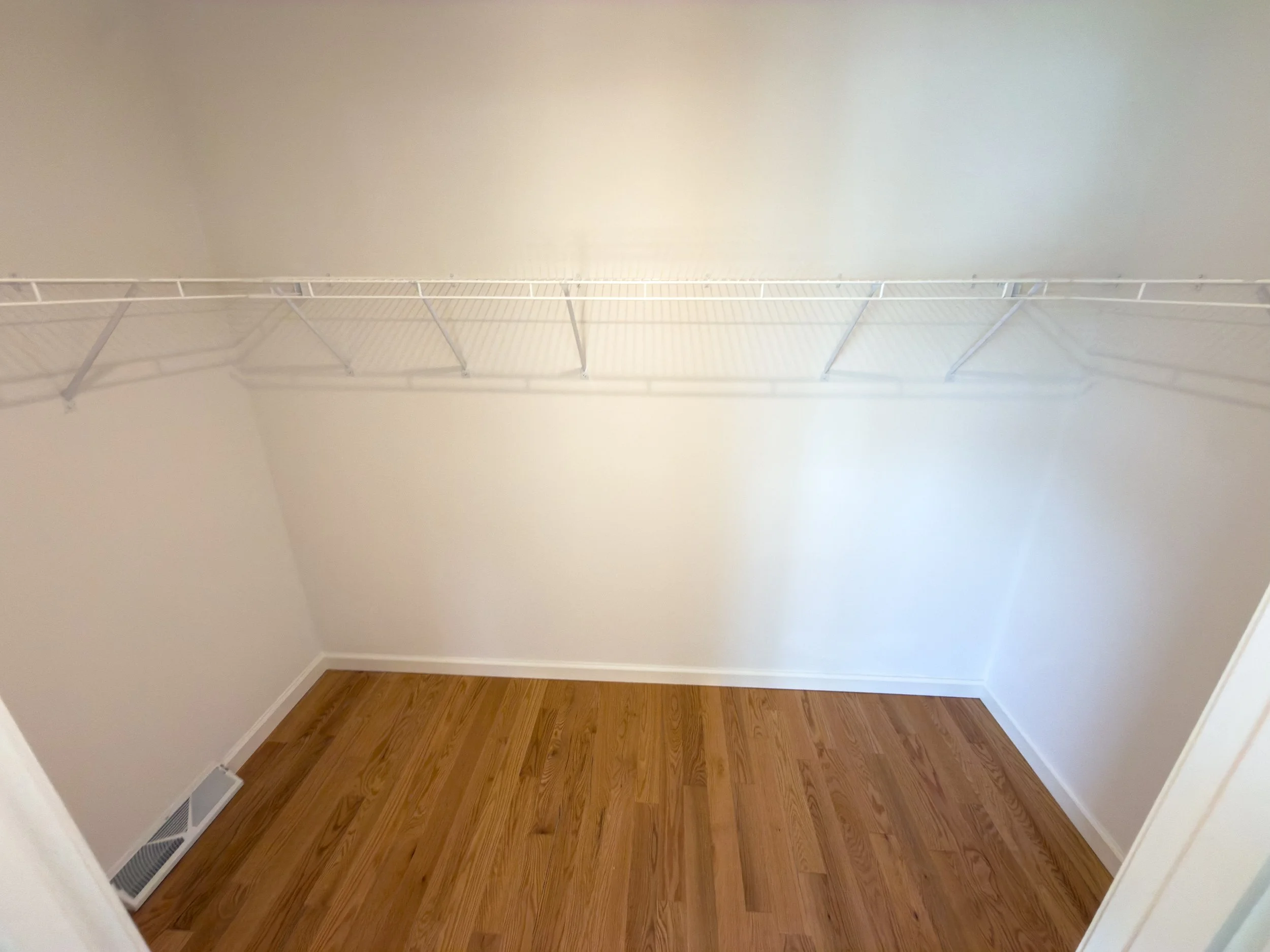 Spacious walk-in closet with wire shelving system, hardwood floors, and white walls — ample built-in storage space in a Manufactured Home