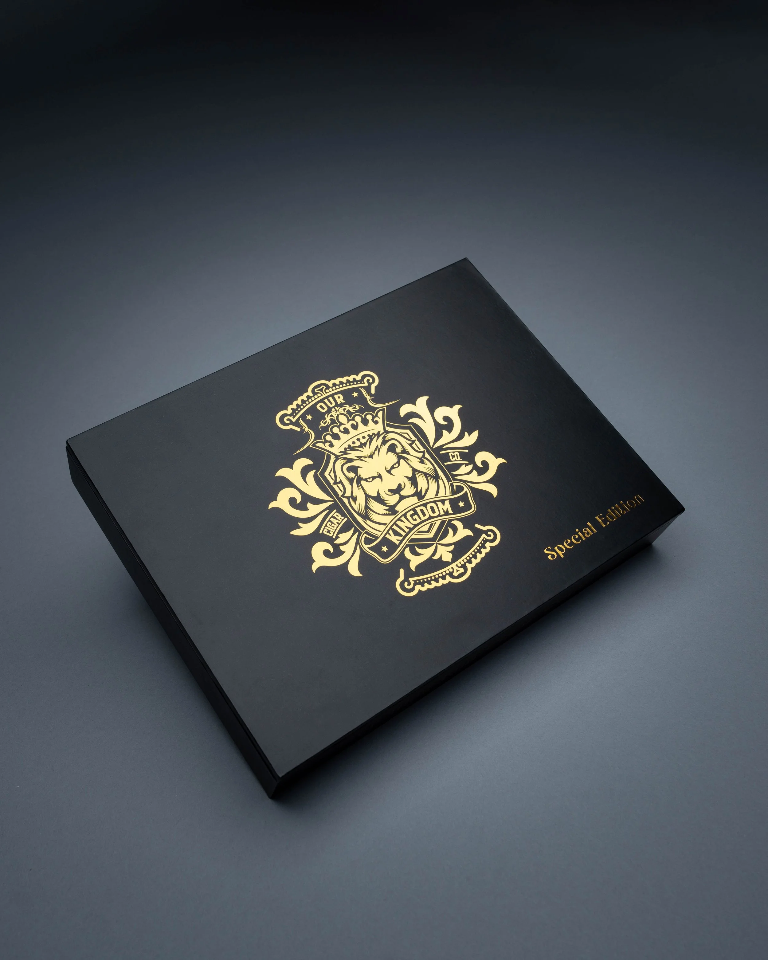 A black box with a gold crest logo featuring a lion's head, crown, and decorative floral elements, with the text 'Our Kingdom' and 'Special Edition'.