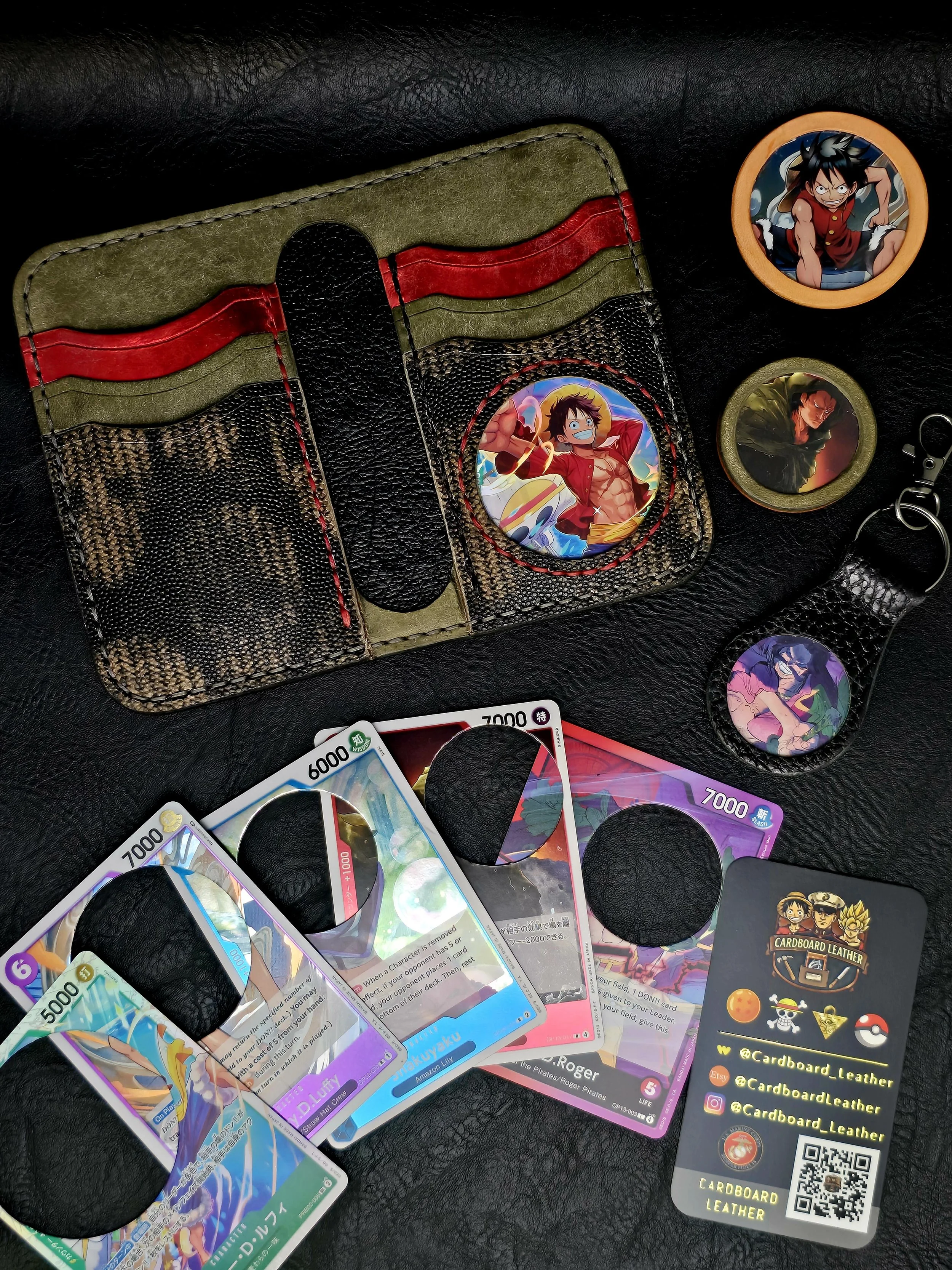 Anime-themed Pokémon trading cards, button pins featuring anime characters, a keychain with anime artwork, and a cardholder with social media details on a black leather surface.