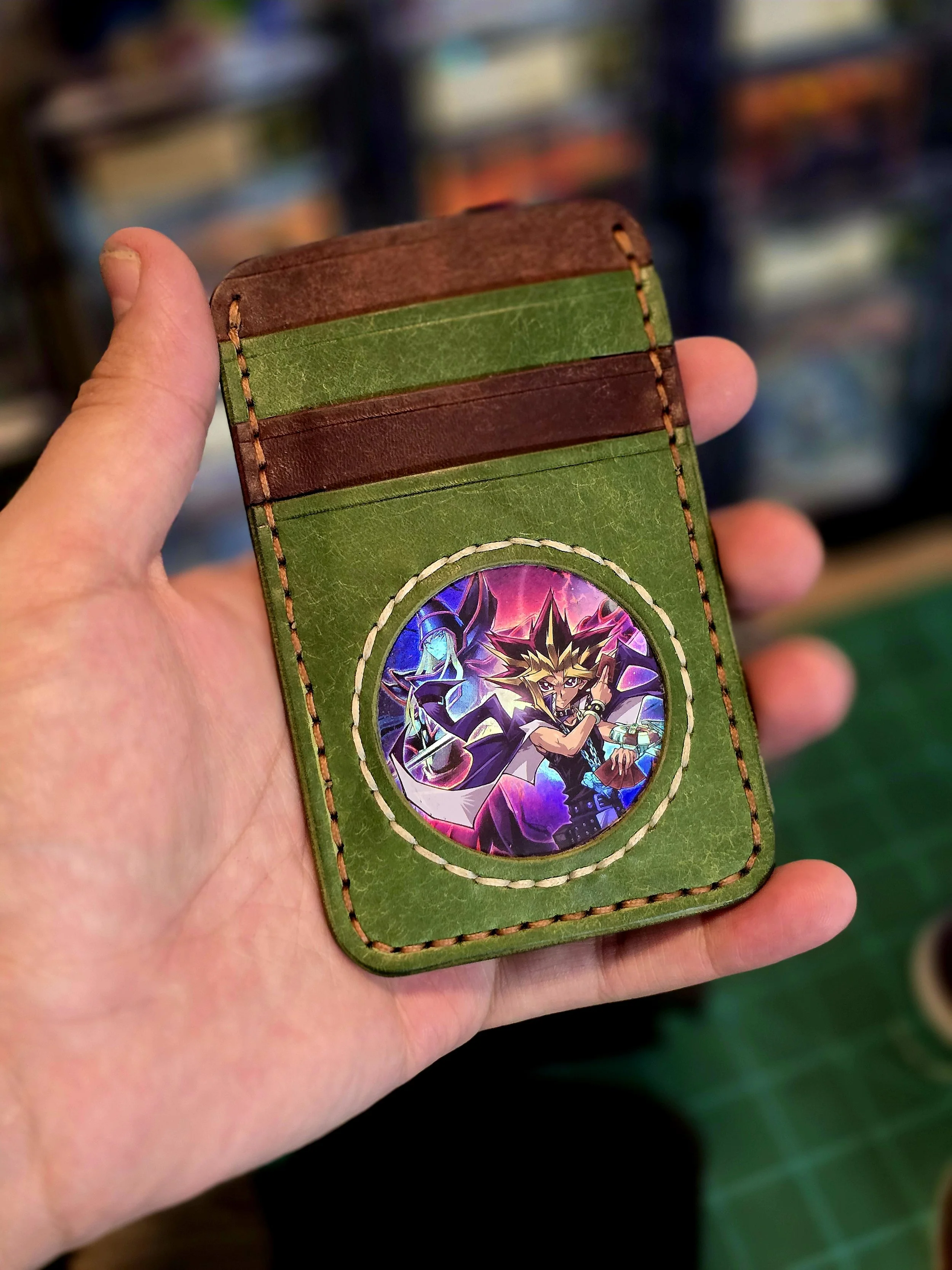 Leather wallet with a circular image of Yugi Muto from Yu-Gi-Oh! on the front, held in a person's hand.