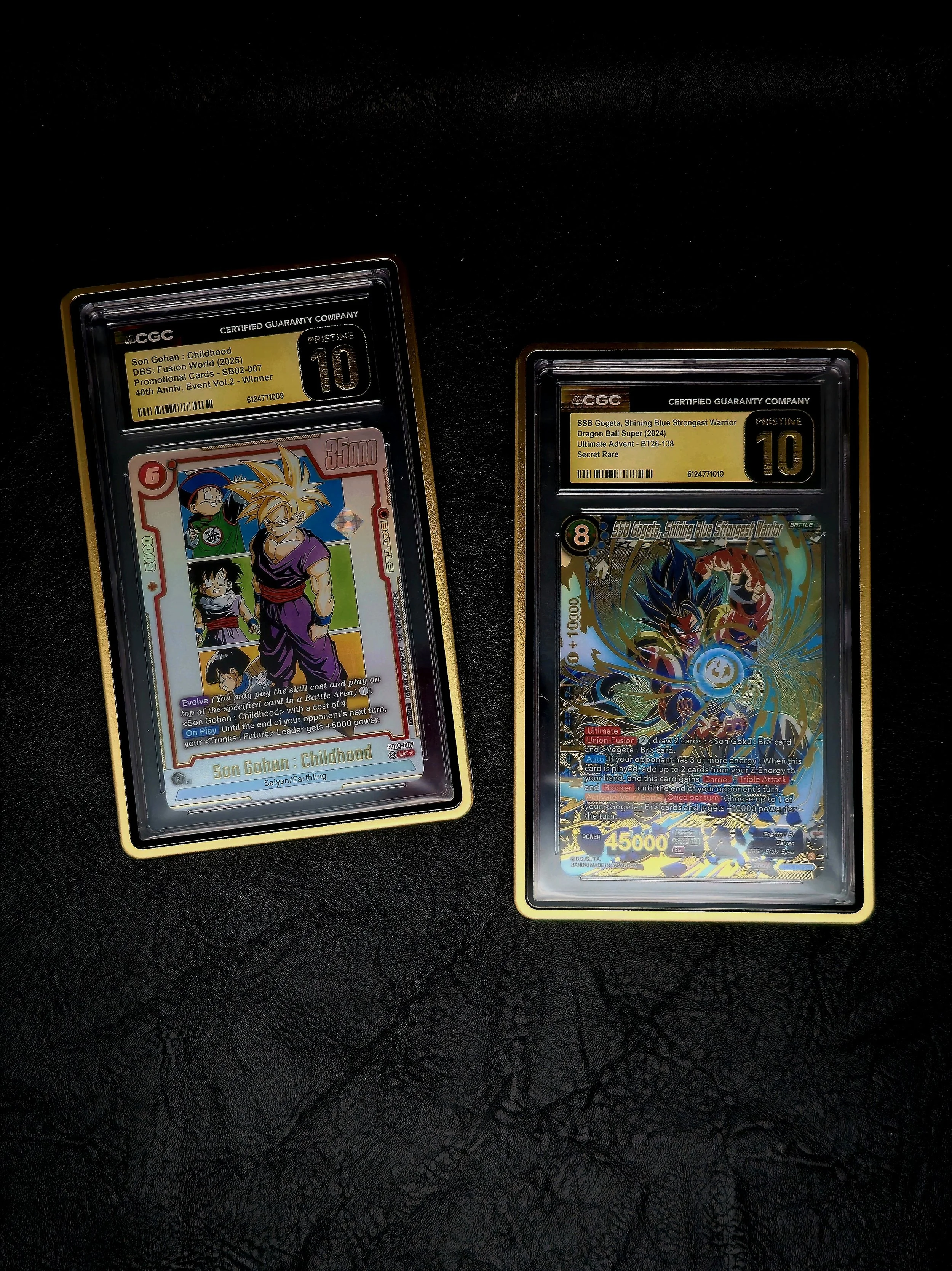 Two graded collectible Dragon Ball Super trading cards inside protective casings are displayed on a black surface. The left card features Son Gohan as a child, with a pink border, and the right card features Son Goku in blue, with a holographic desig